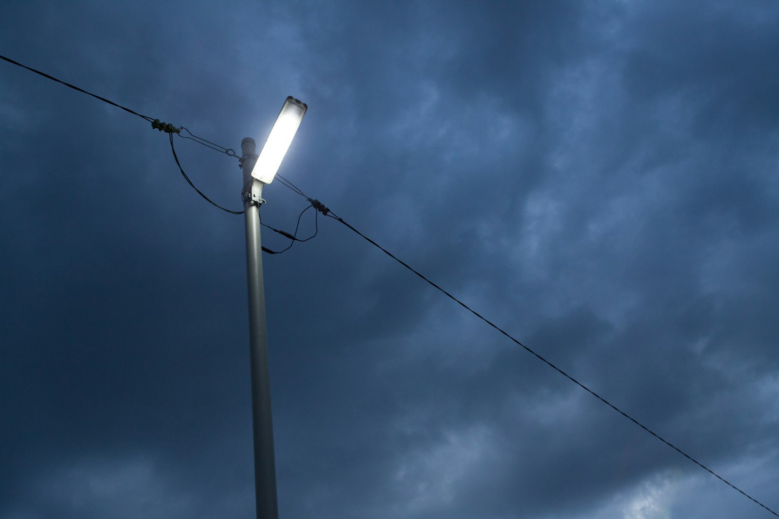 在黑暗天空下的街燈和電線的照片