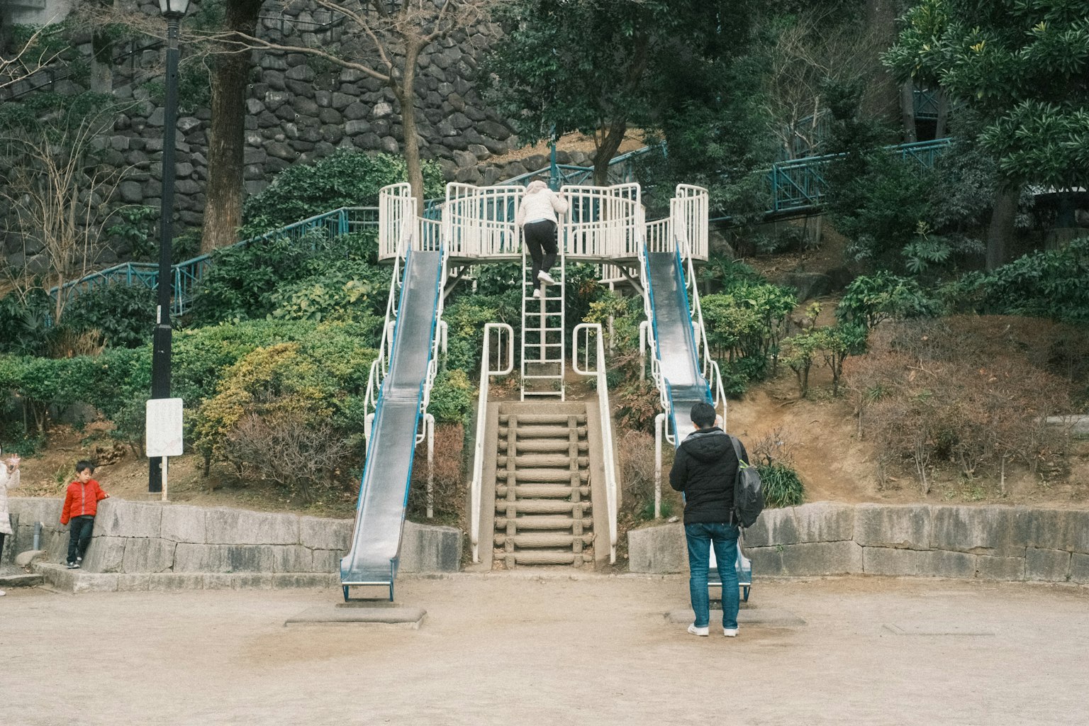 Una scena di parco con scivoli e scale con bambini e adulti