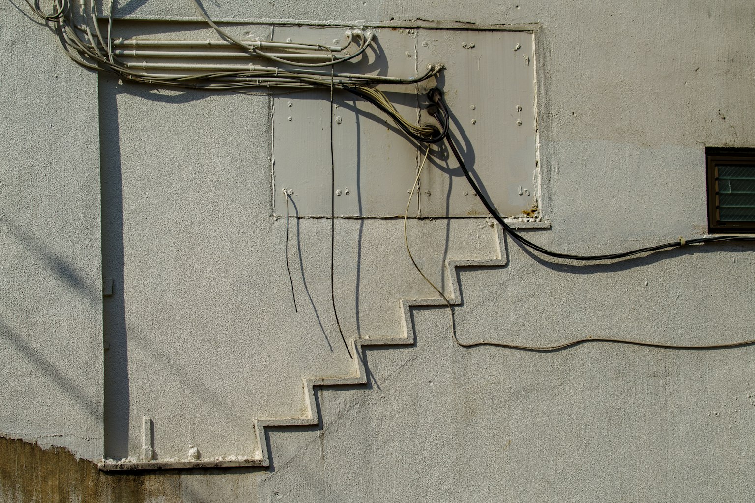 Treppe-ähnliches Design an einer weißen Wand mit verhedderten Drähten