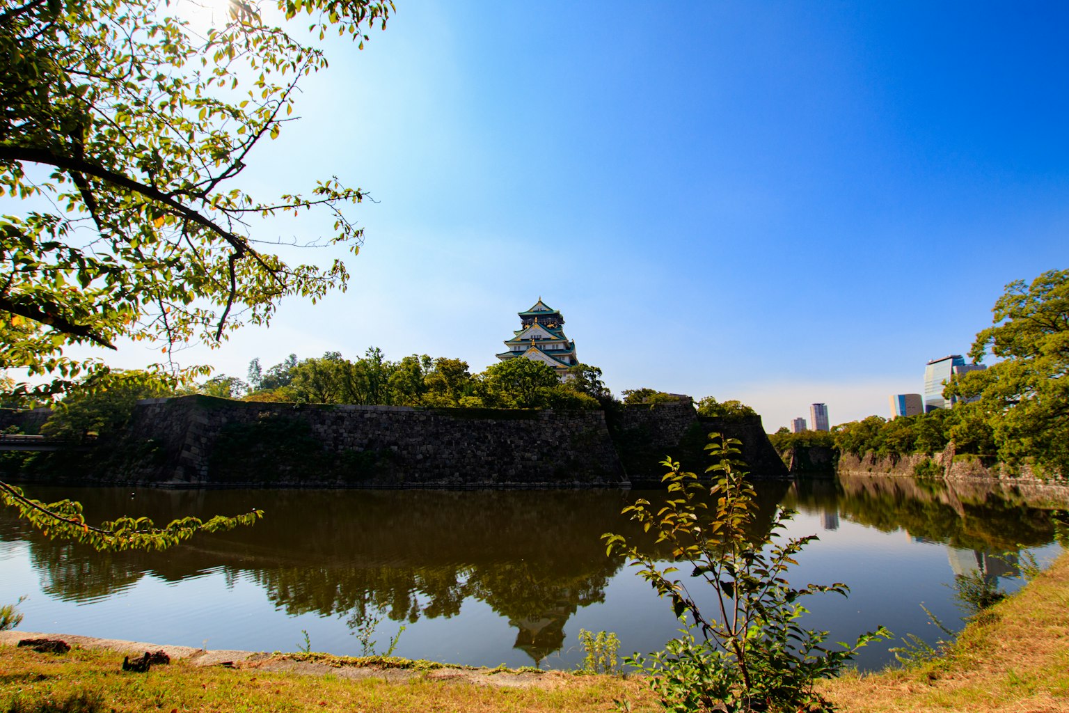 Vista panoramica di un castello riflesso in uno stagno sereno sotto un cielo blu chiaro