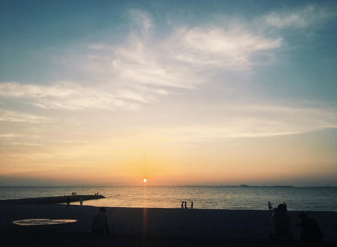 夕暮れの海辺で水平線に沈む夕日