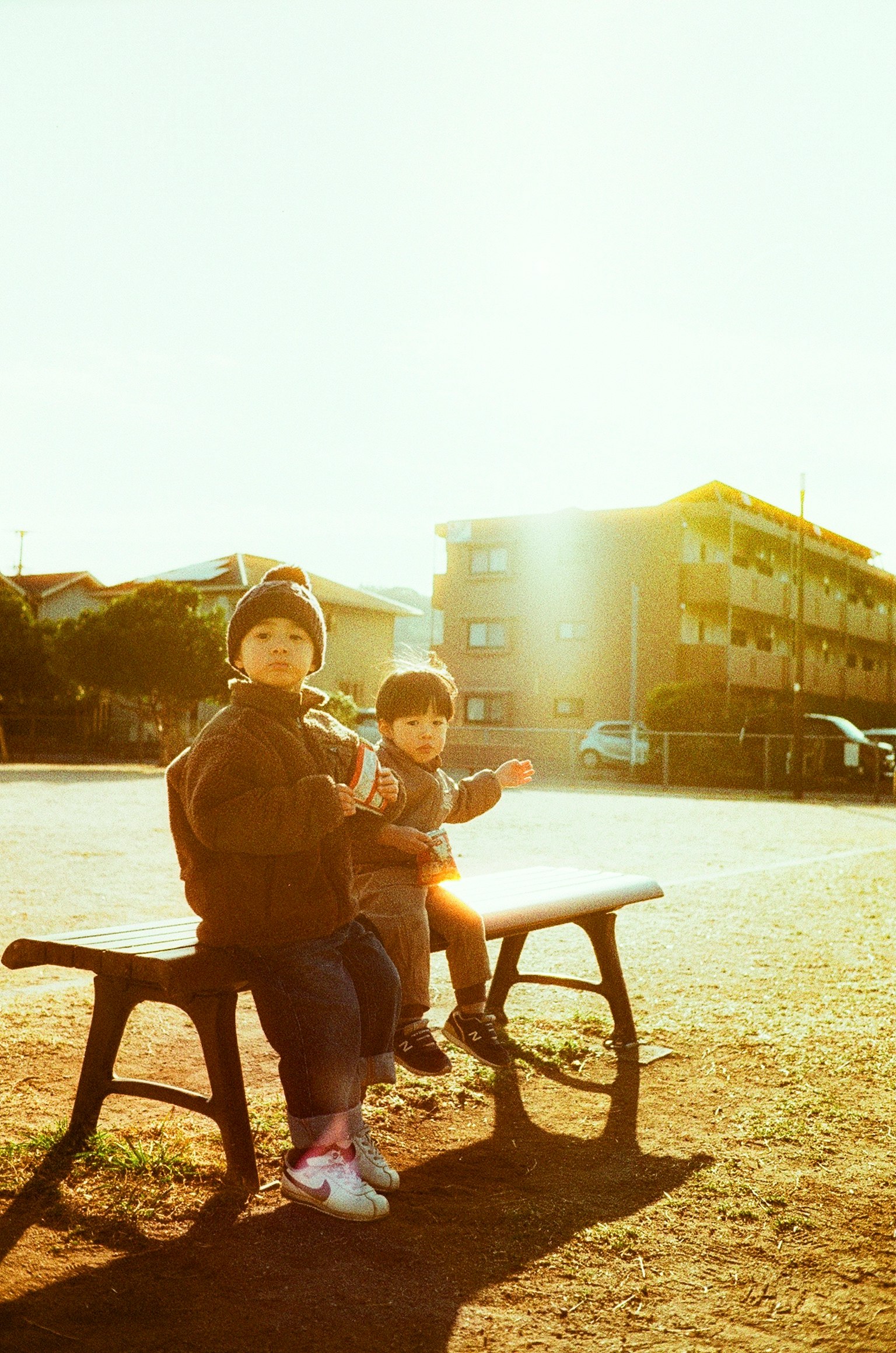 Due bambini seduti su una panchina del parco con la luce del sole in un'atmosfera calda