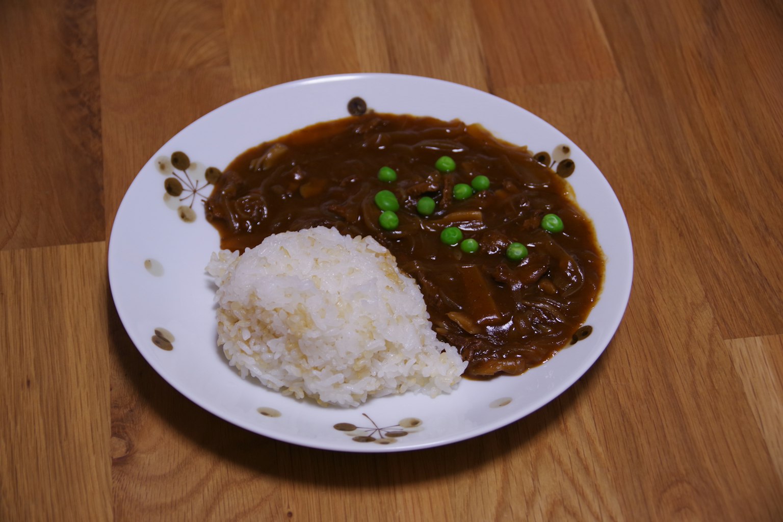 Plate of curry sauce with rice and green peas