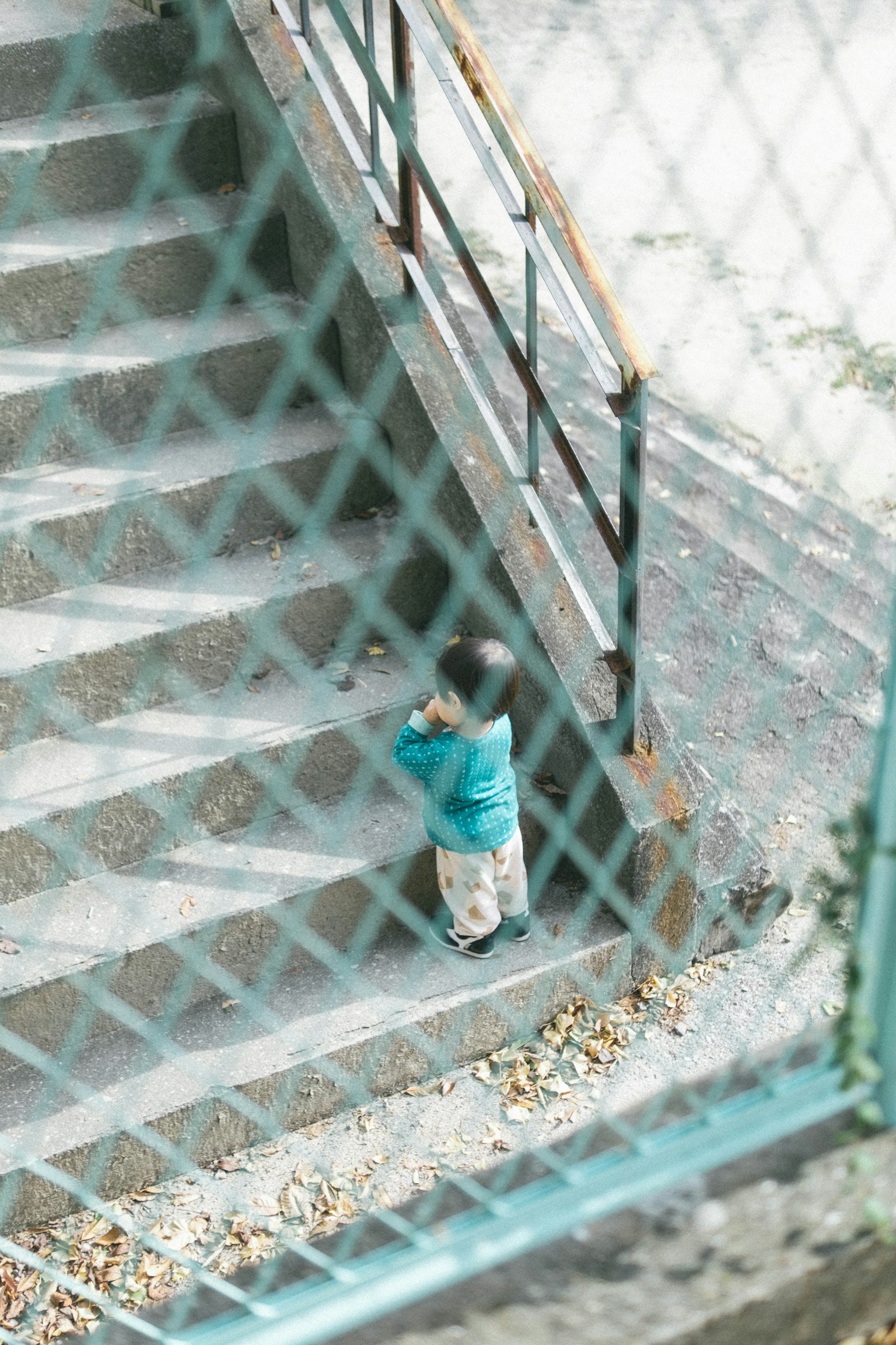 Kind, das Treppen steigt, gesehen durch einen Zaun