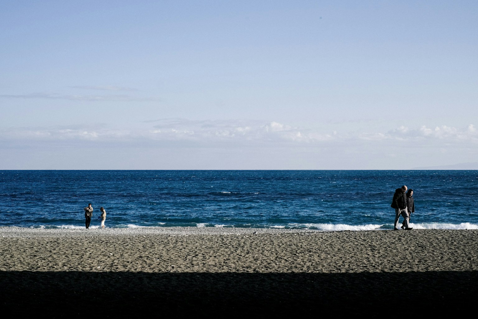 Une plage pittoresque avec des personnes se promenant le long du rivage et un océan bleu