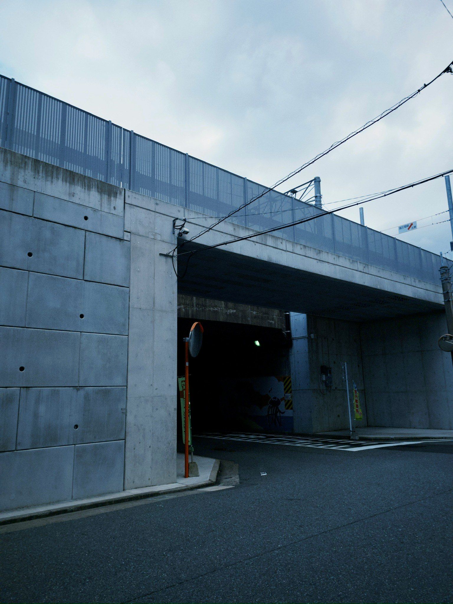 高いコンクリート壁とトンネル状の通路がある屋外の路地