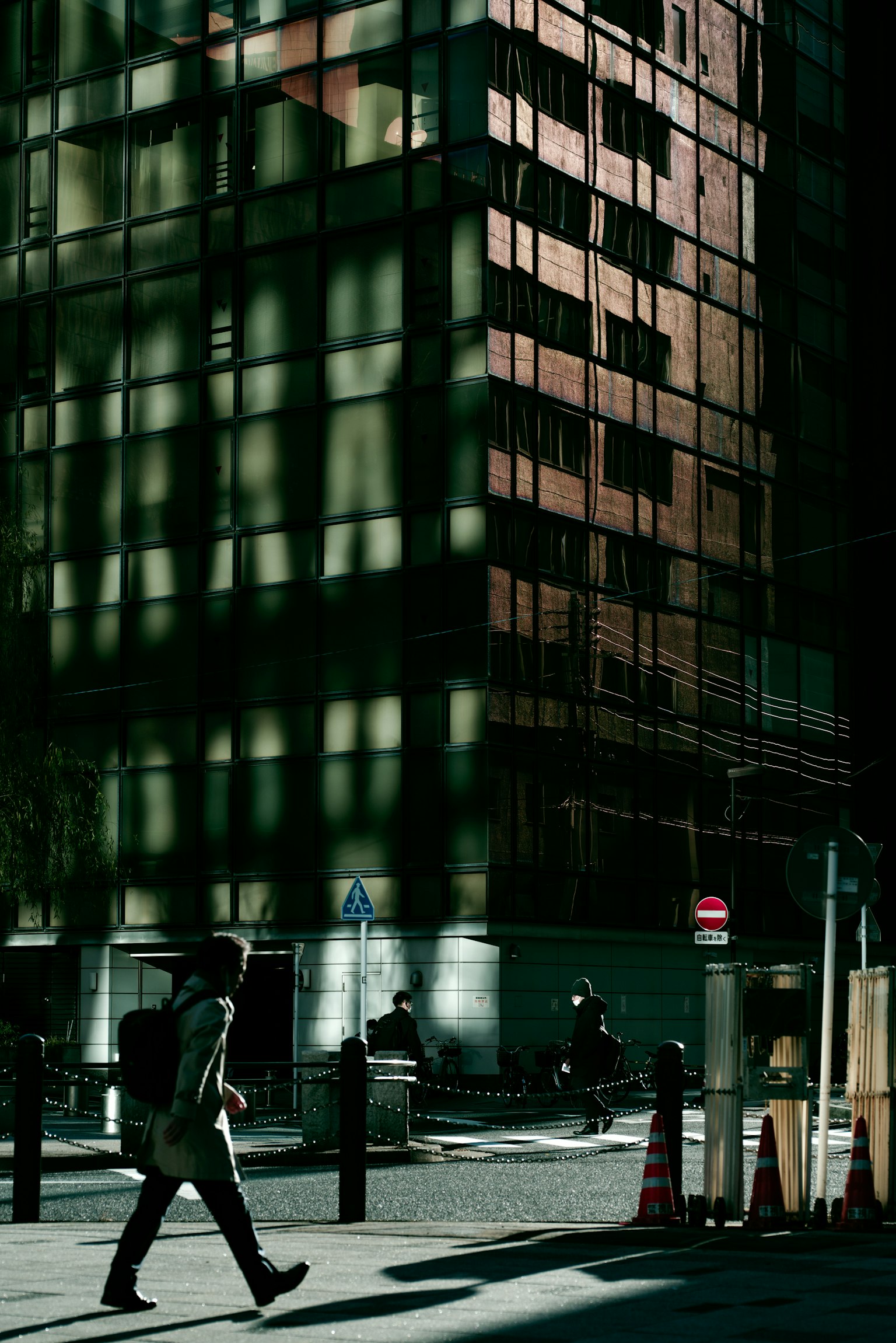 Một người đi bộ qua một tòa nhà với bóng và ánh sáng tương phản