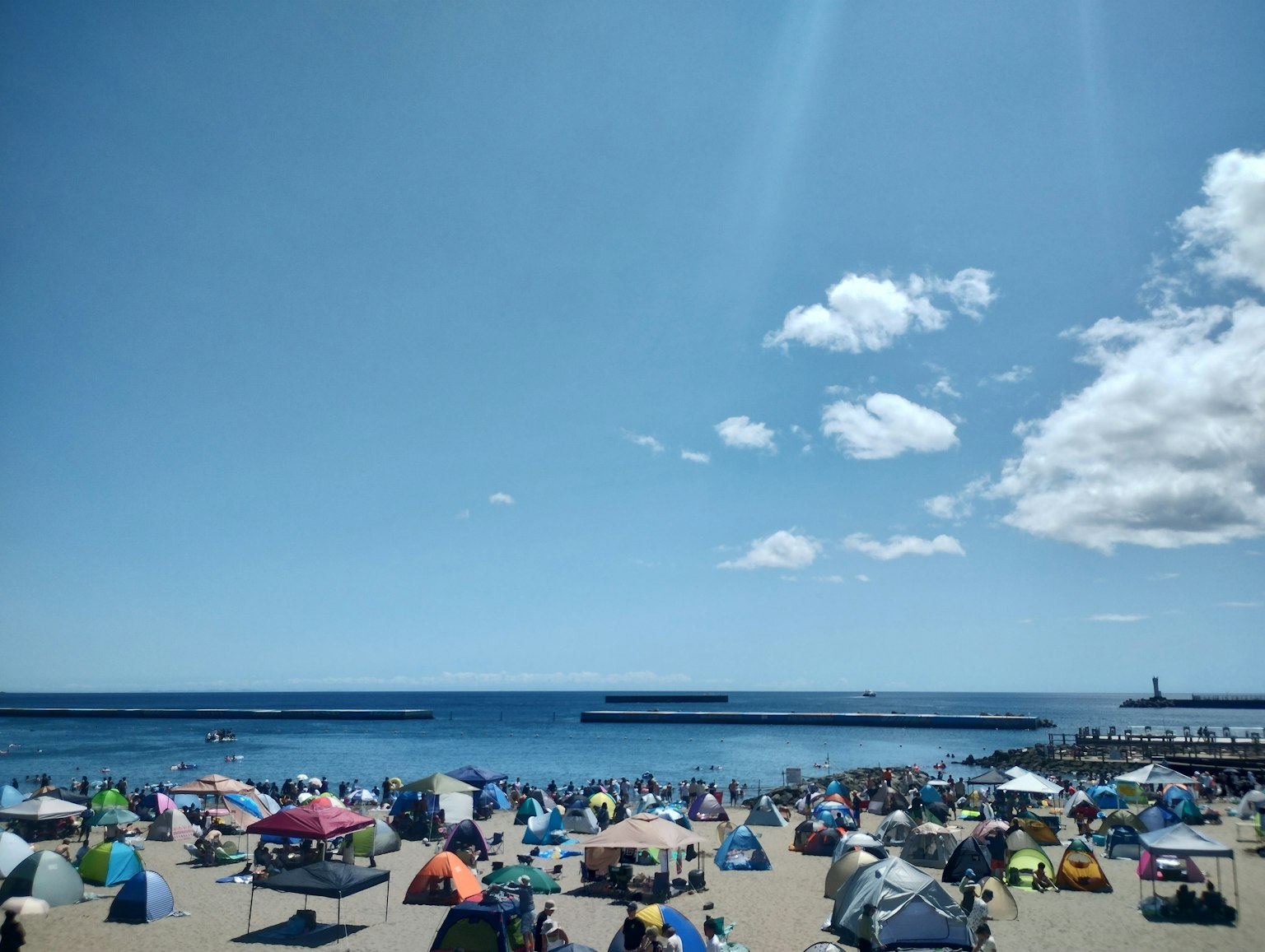海灘場景，五顏六色的帳篷在晴朗的藍天和海洋下