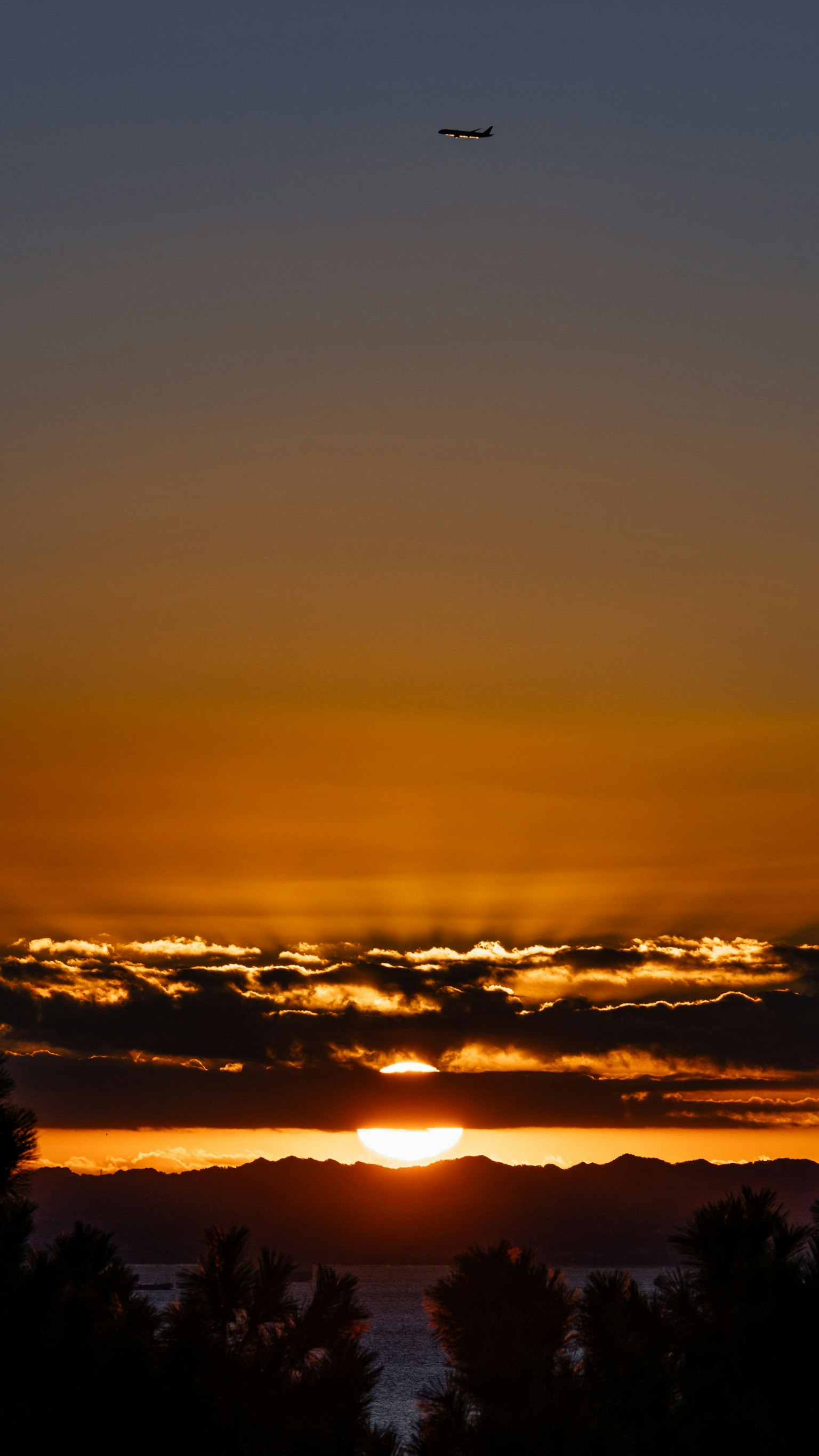 美麗的日落透過雲層可見，天空中有一架飛機飛過