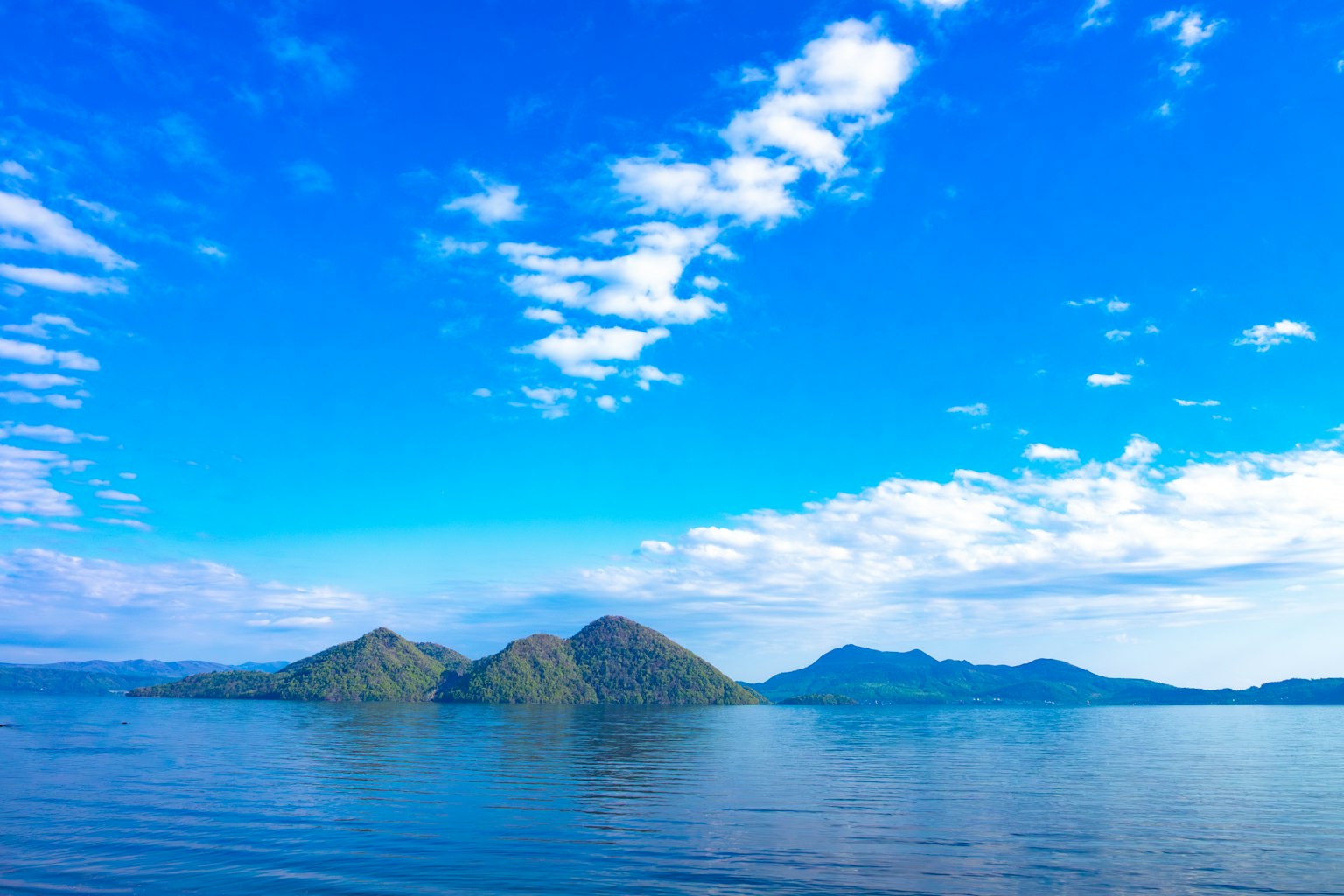Green islands floating on calm waters under a blue sky