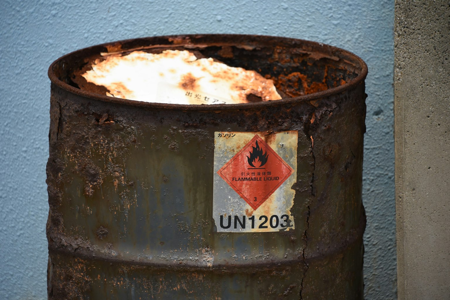 Rusty drum barrel with fire and hazardous material label