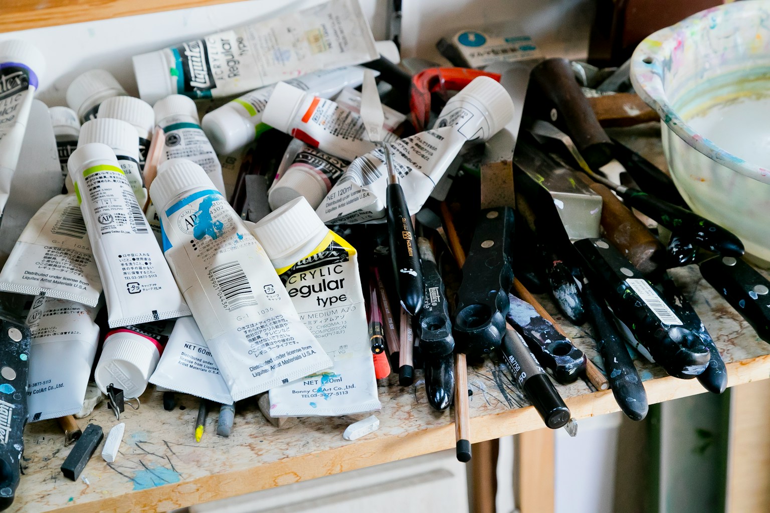 Meja kerja berantakan dengan tabung cat dan kuas