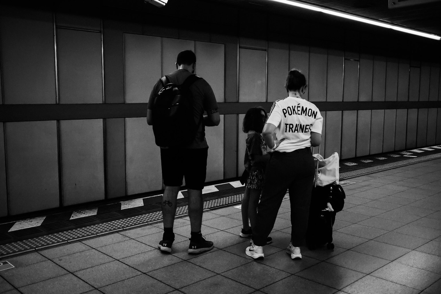 Two men and one woman waiting on a train platform