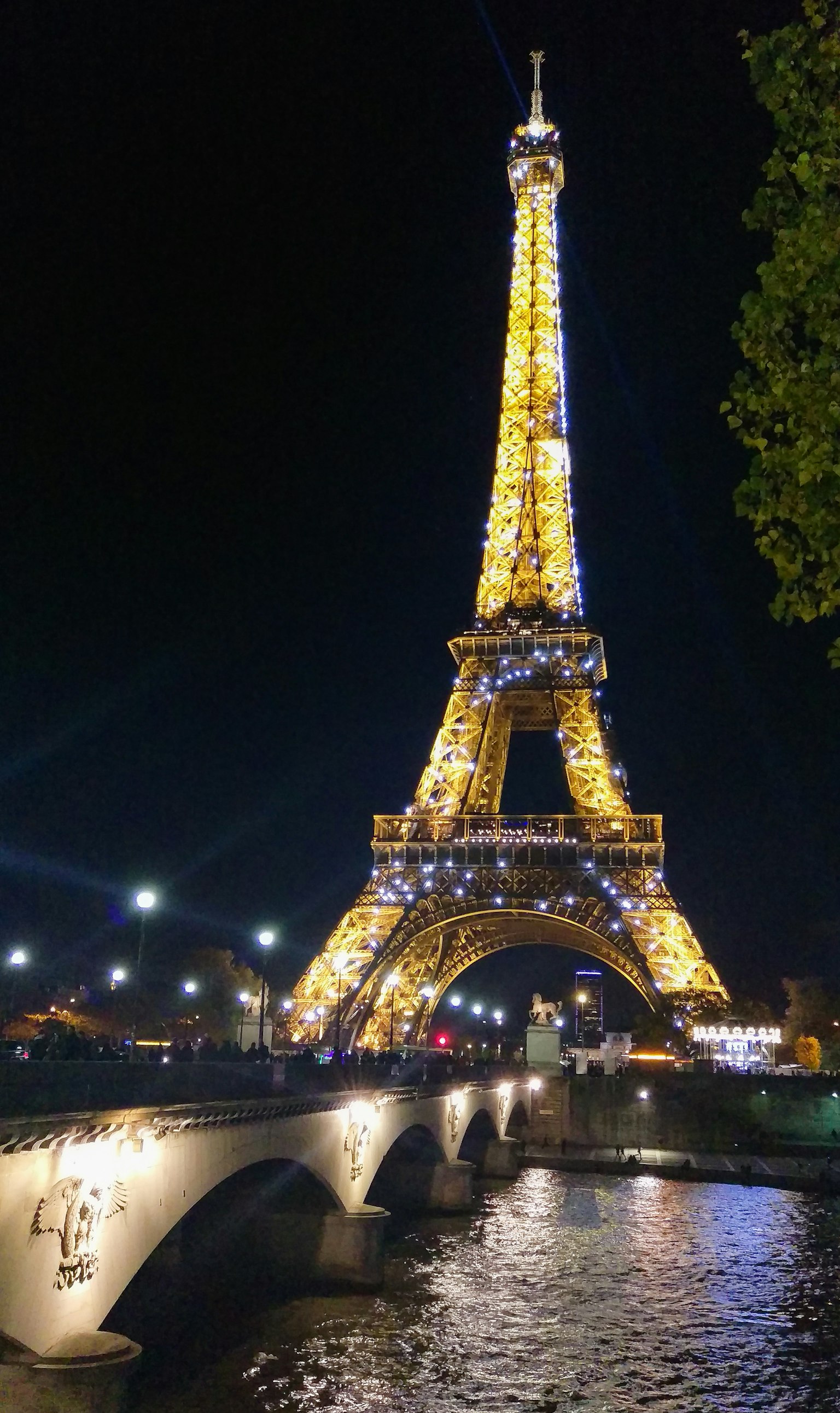 夜晚燈光照亮的艾菲爾鐵塔,河流和橋在視野中