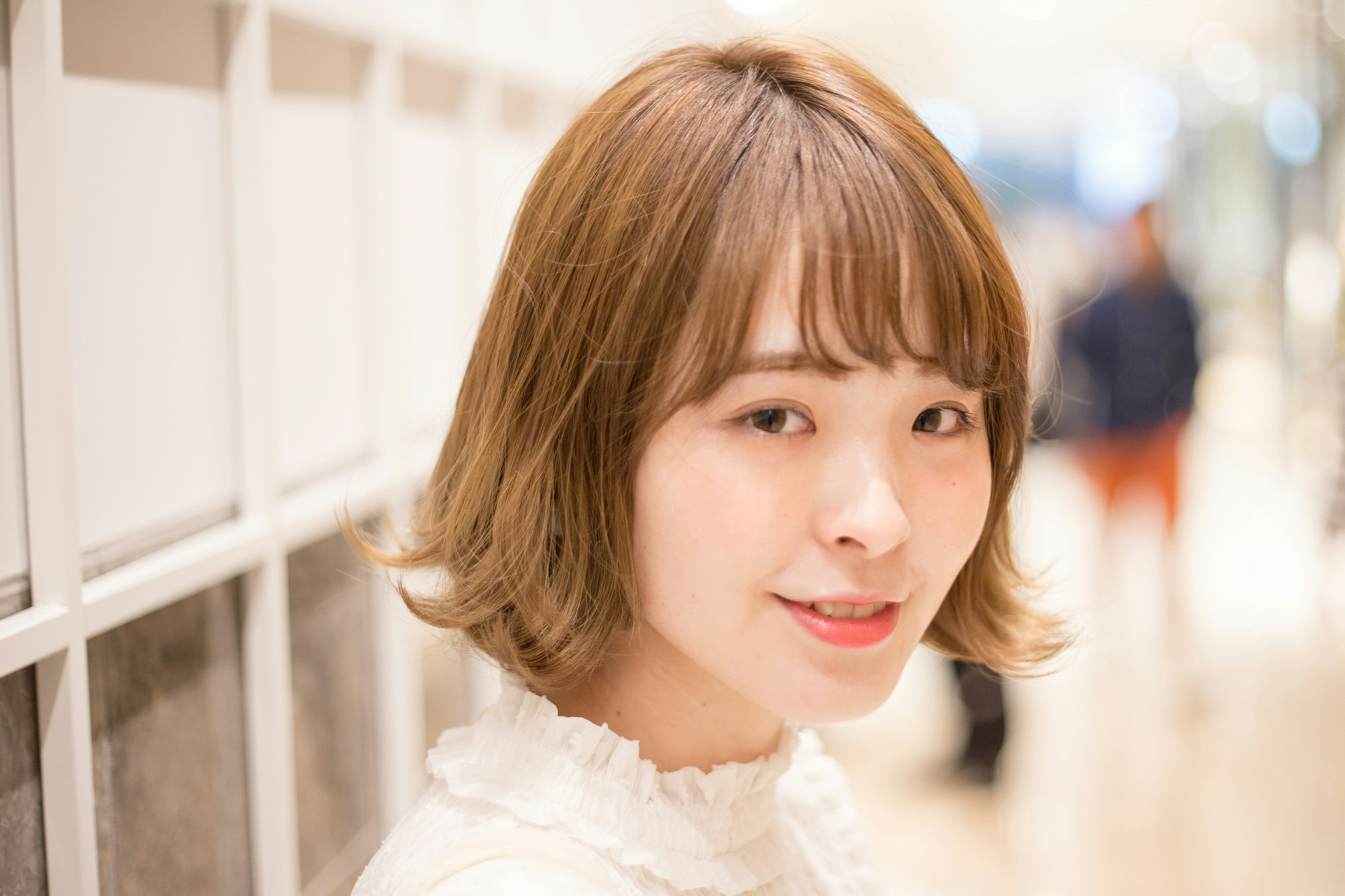 白い壁の前で微笑む女性のポートレート