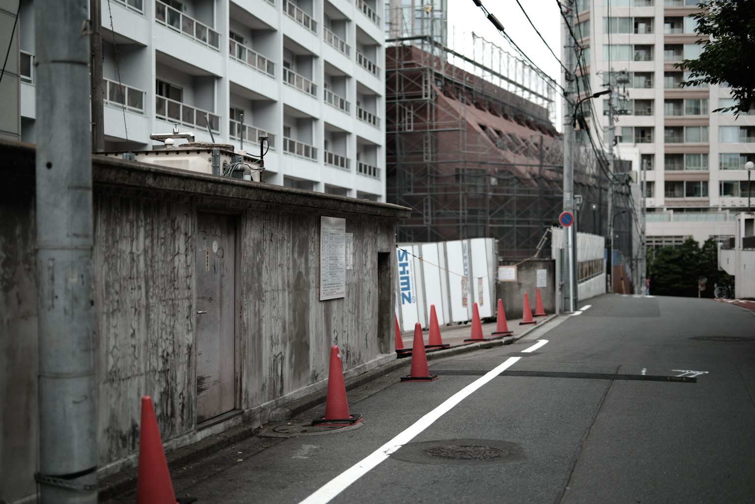ทิวทัศน์ถนนที่มีสถานที่ก่อสร้างและกำแพงคอนกรีตพร้อมกรวยสีแดง