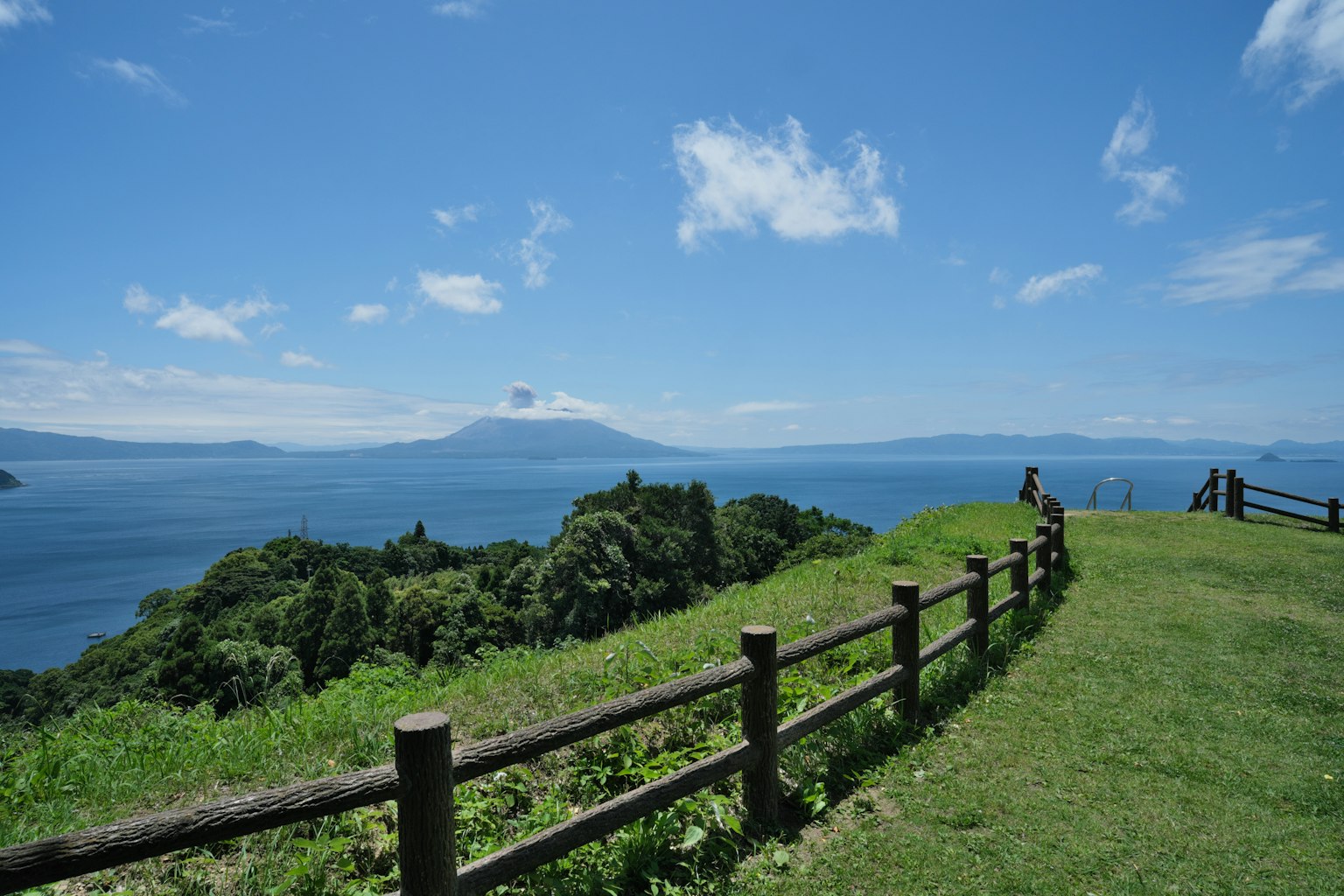 一幅风景如画的景色，蓝天和绿色草地，背景有湖泊和山脉