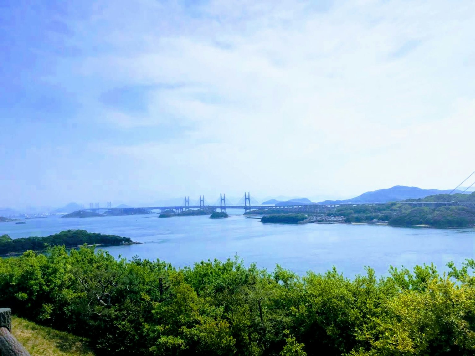 Cảnh đẹp của bầu trời xanh và nước cây cối xanh tươi ở phía trước cầu có thể nhìn thấy ở xa