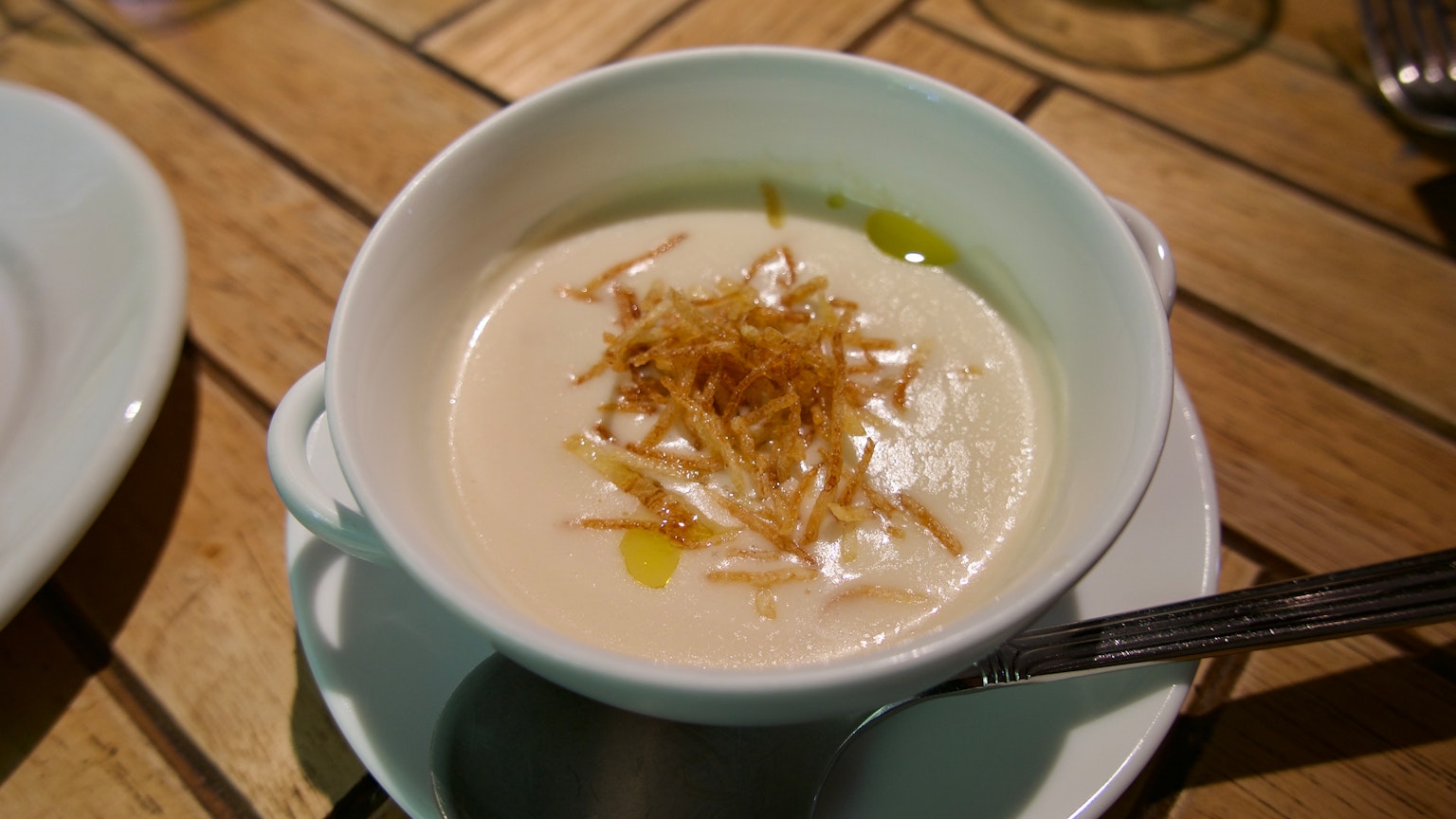 Soupe crémeuse garnie d'oignons frits croustillants servie dans un bol blanc
