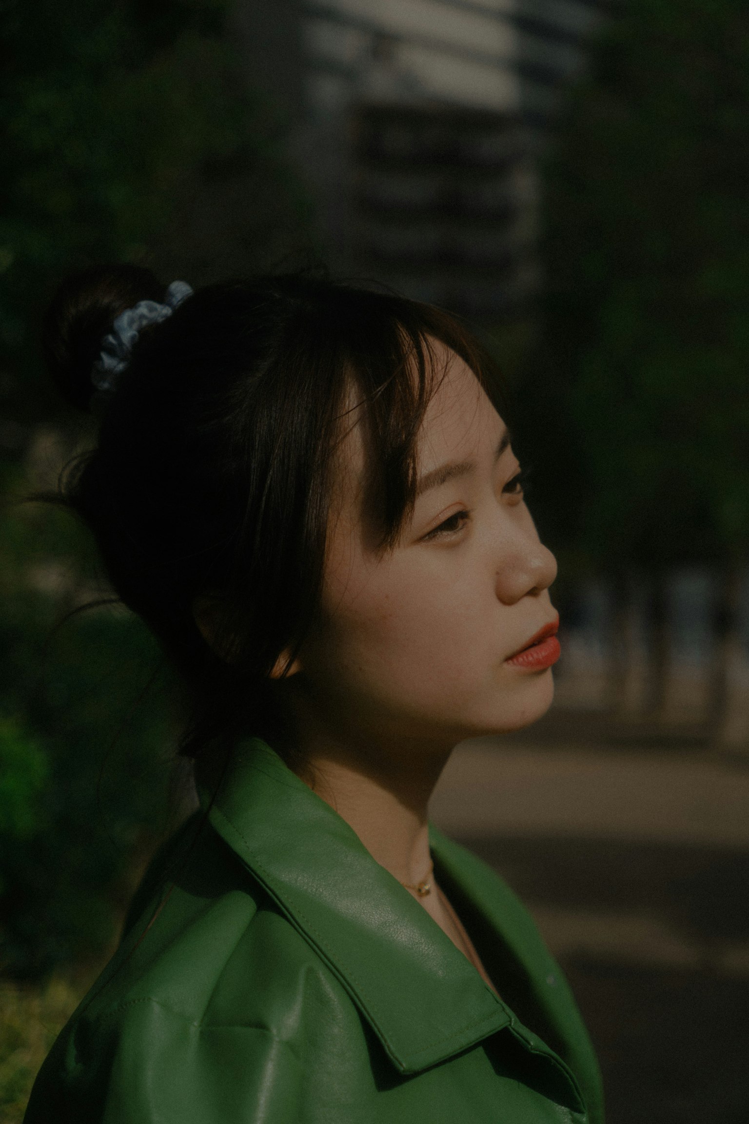A woman in a green coat looking sideways with soft natural light illuminating her face