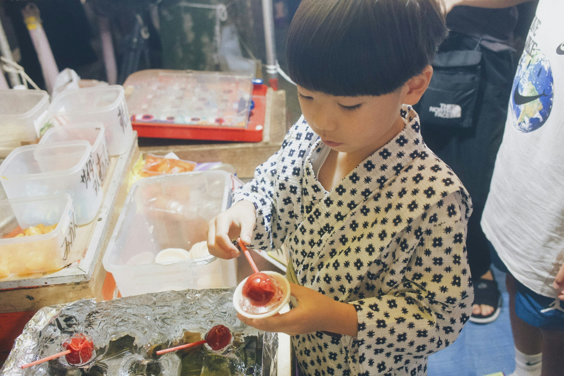 Child scooping sauce at a street-food stall