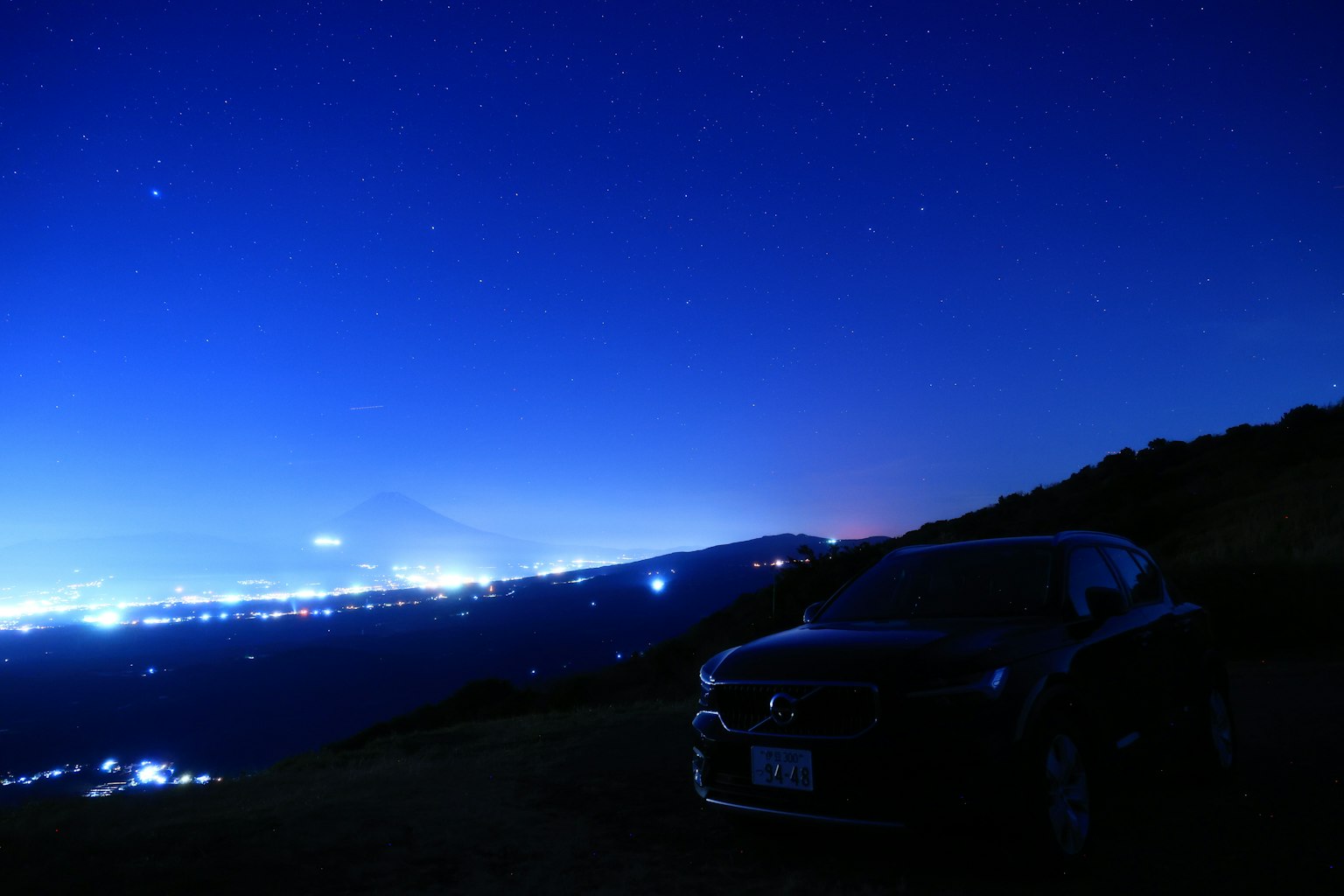 星空下汽车轮廓与城市灯光背景