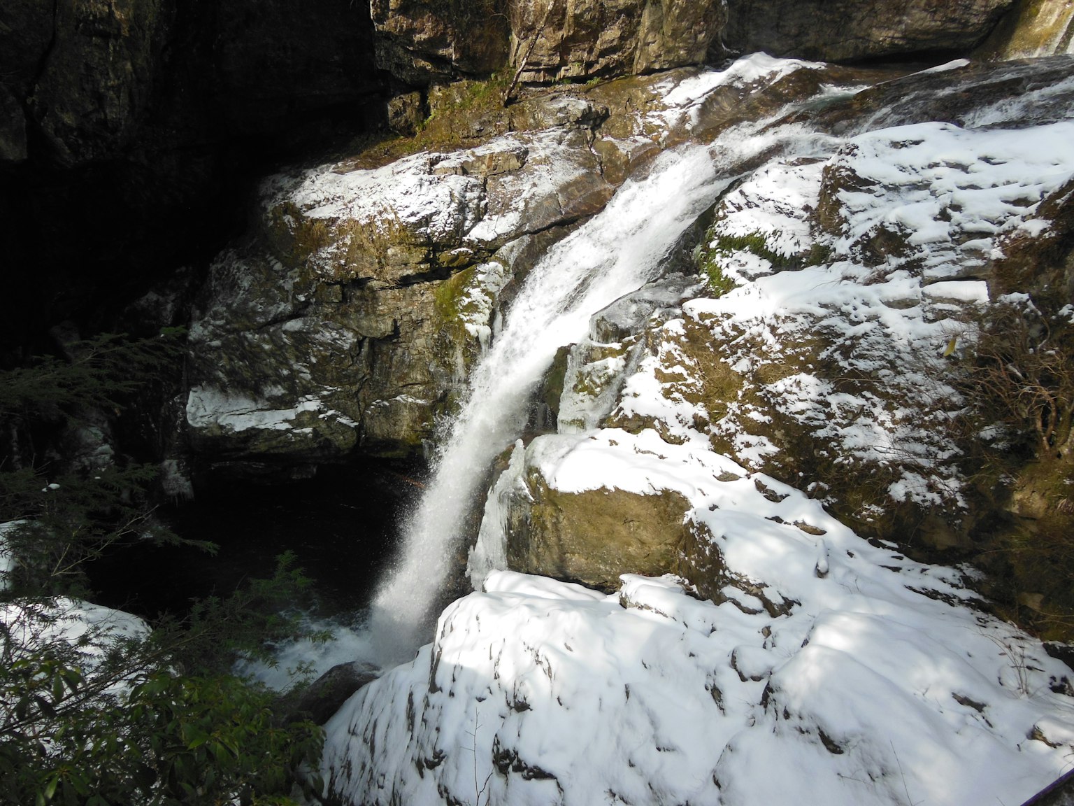Petite cascade coulant entre des rochers recouverts de neige