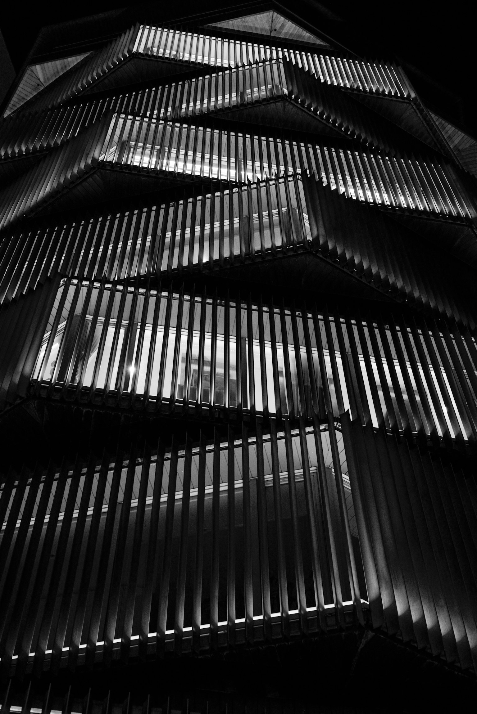 Modern building facade in urban night scene featuring zigzag design and illuminated elements
