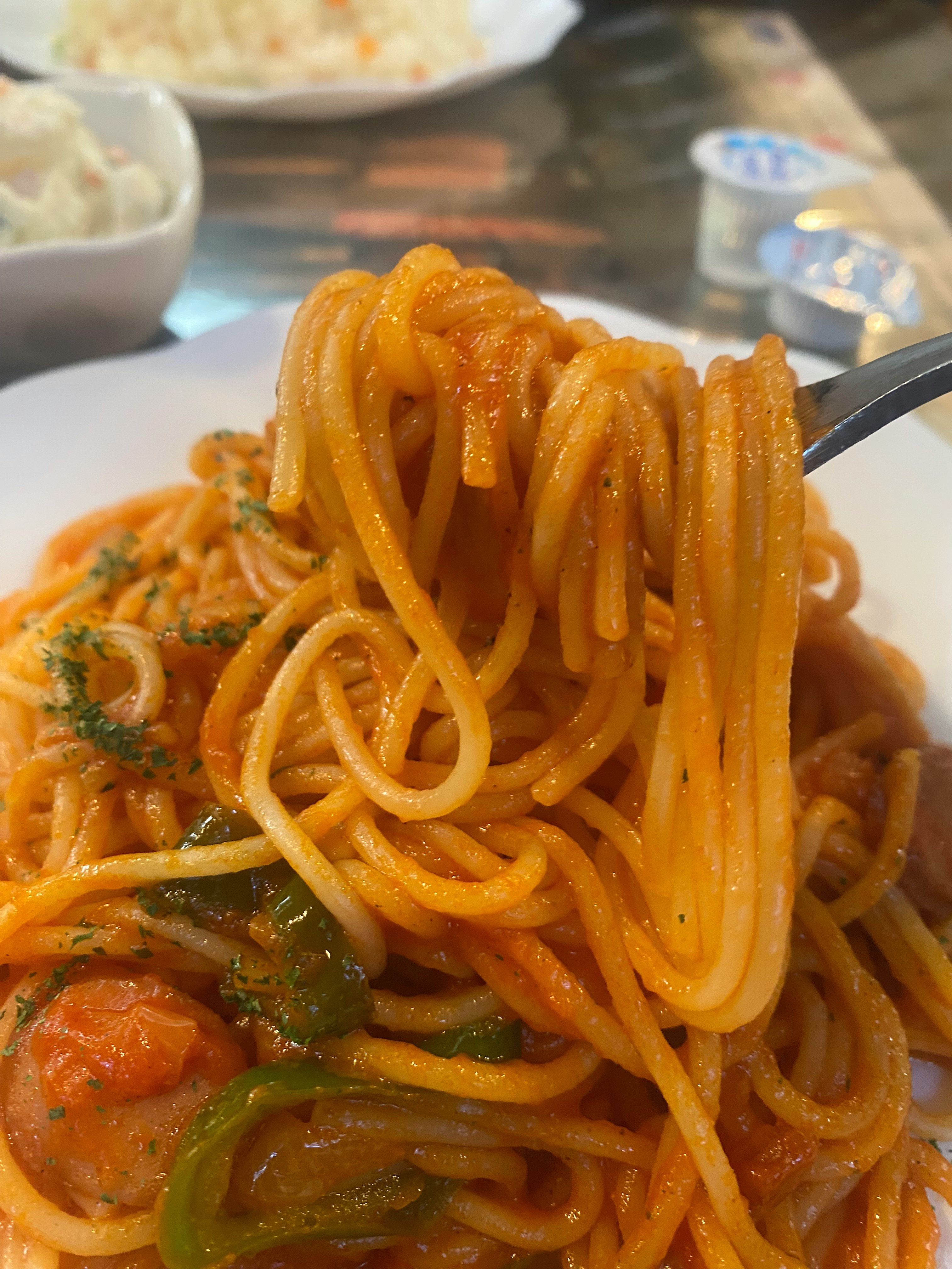 Spaghetti napoletani sollevati con la forchetta su un tavolo