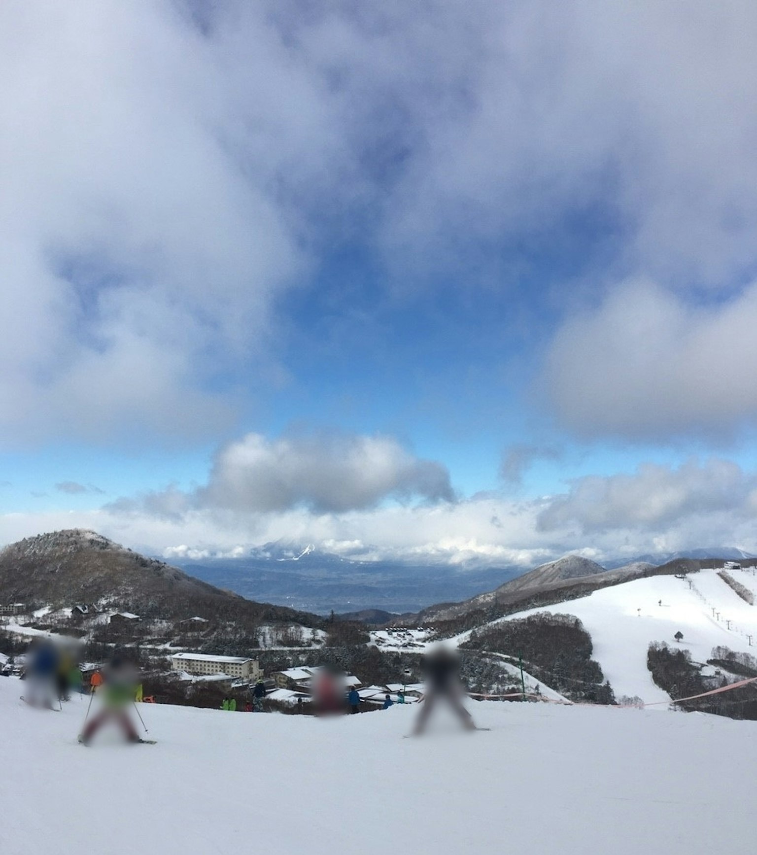 人们在雪山上滑雪，背景是云朵和蓝天