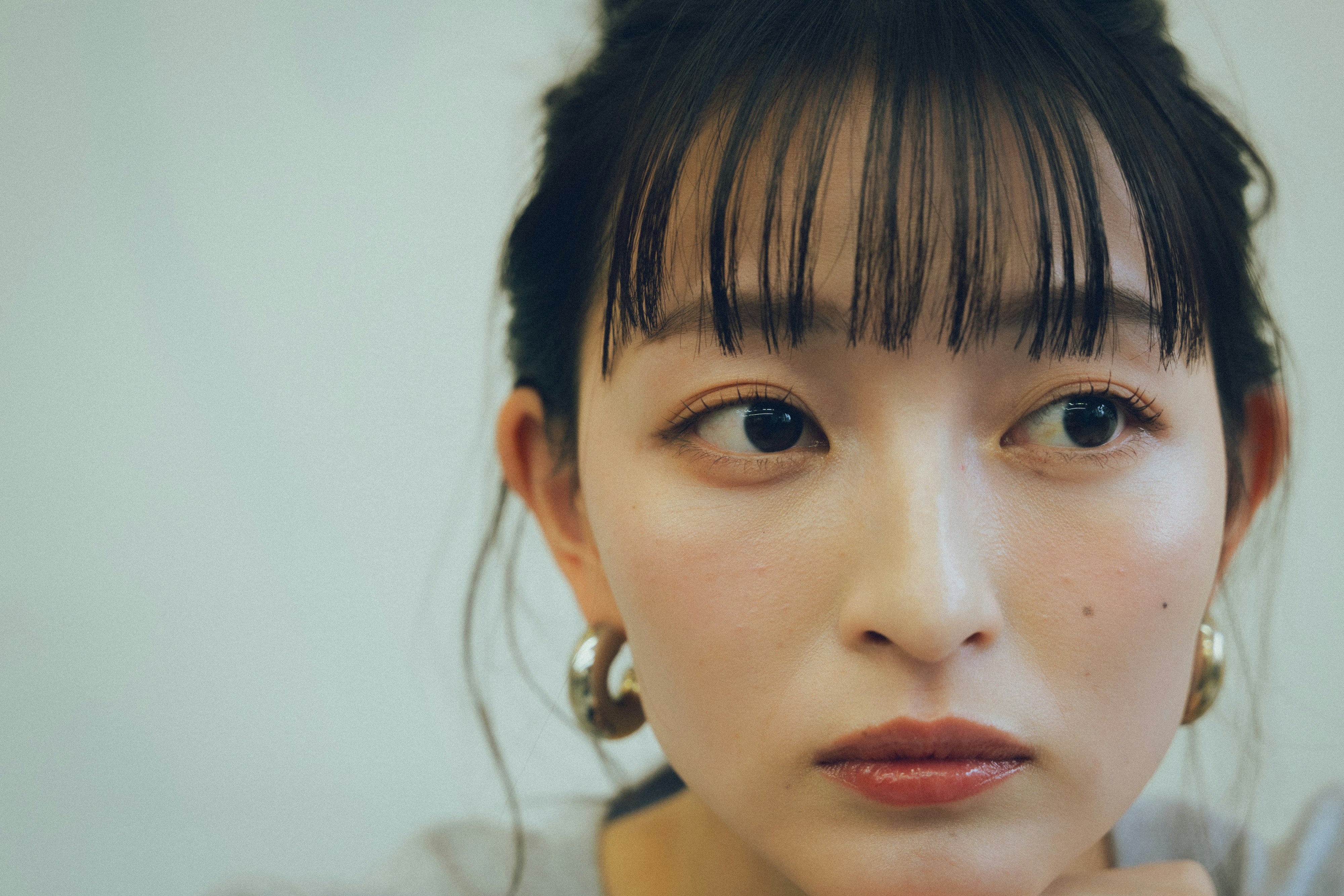 白背景のクールな表情の女性のアップ