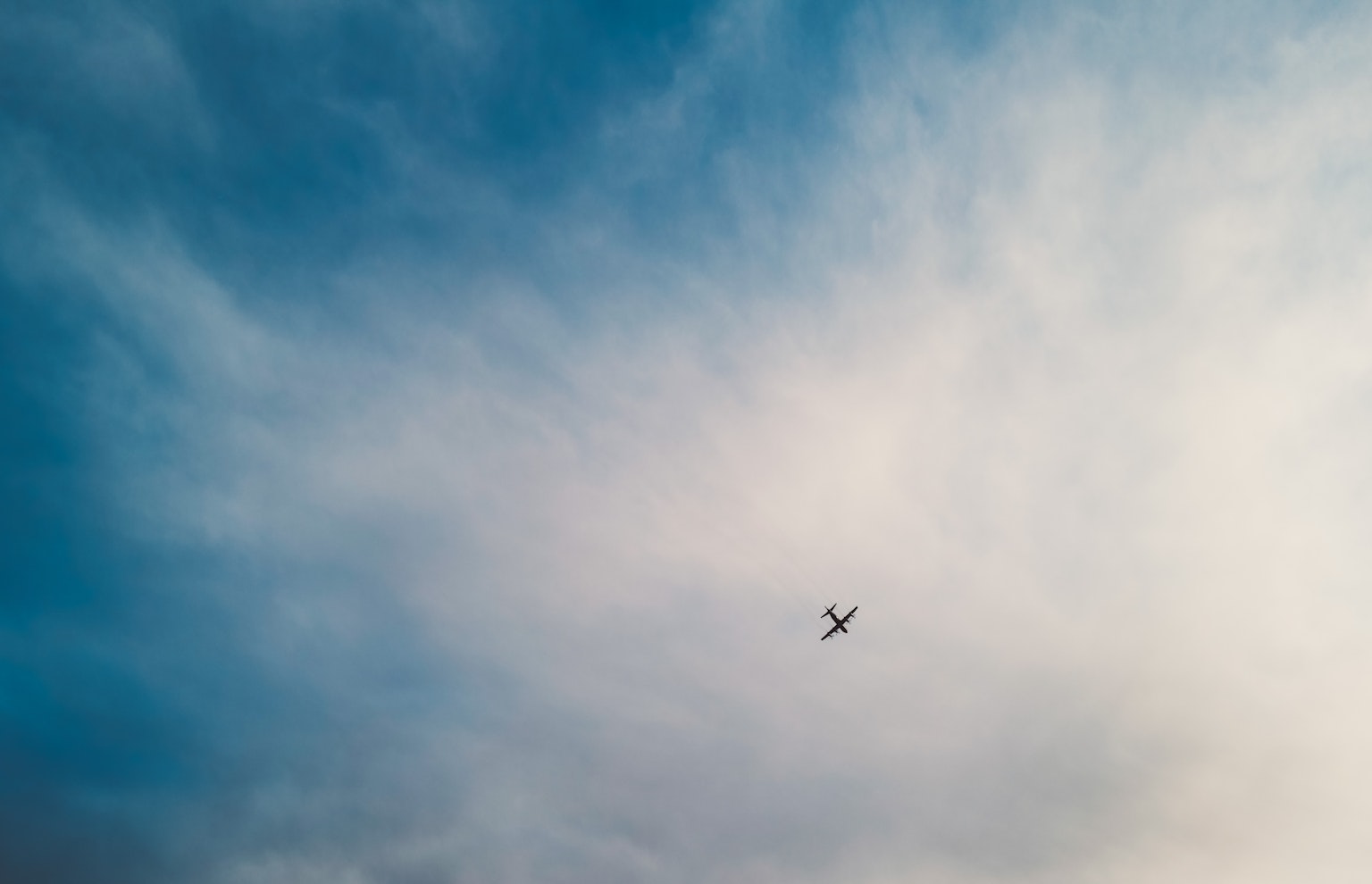 Airplane flying in a blue sky with wispy clouds