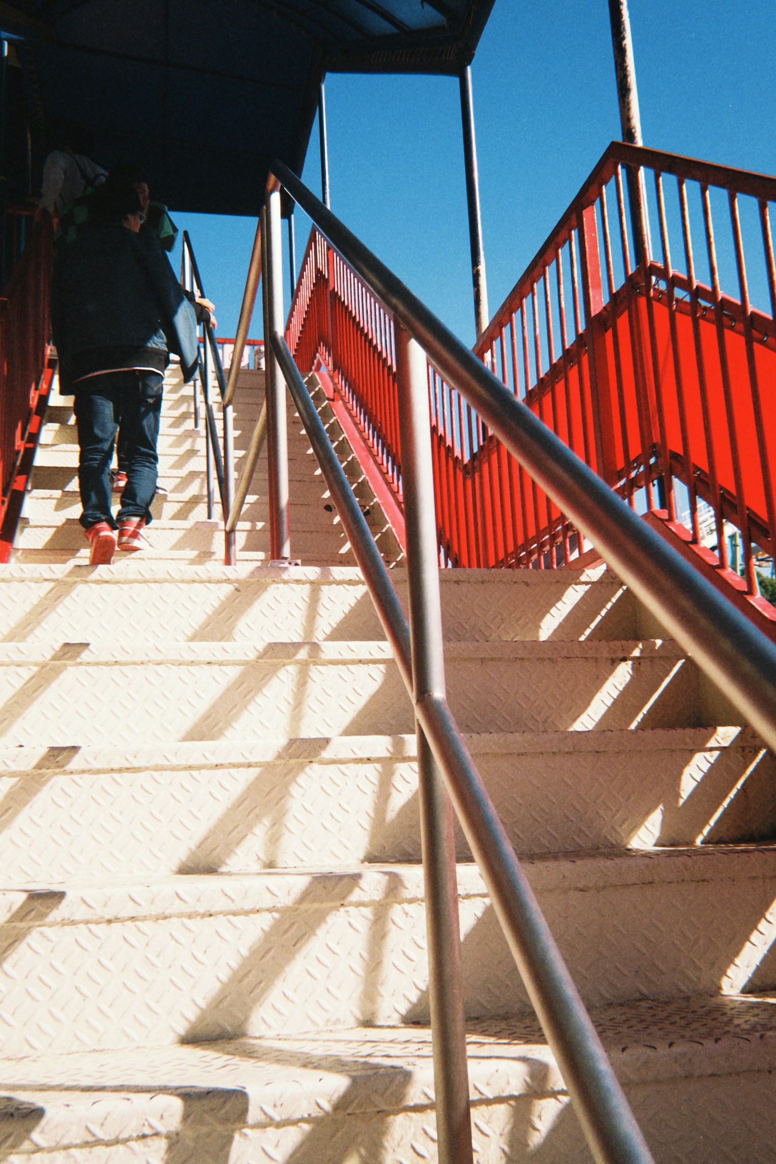 A person walking up a staircase with red railings