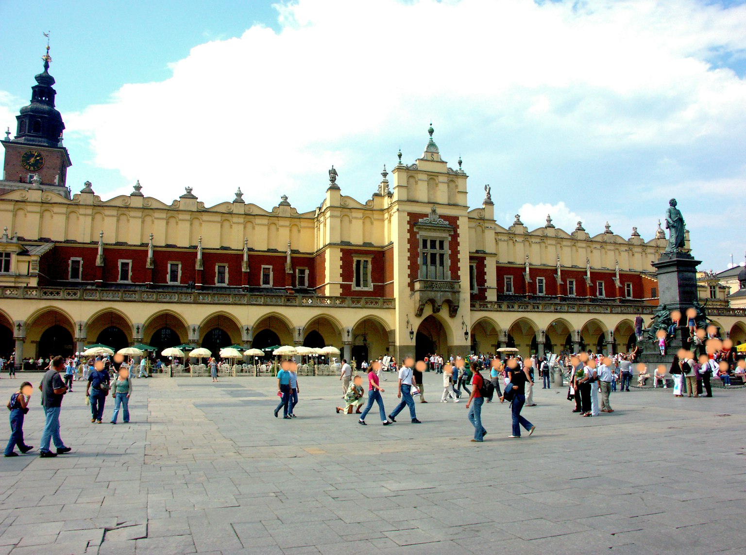 Edificio storico nella piazza del mercato di Cracovia con persone che camminano