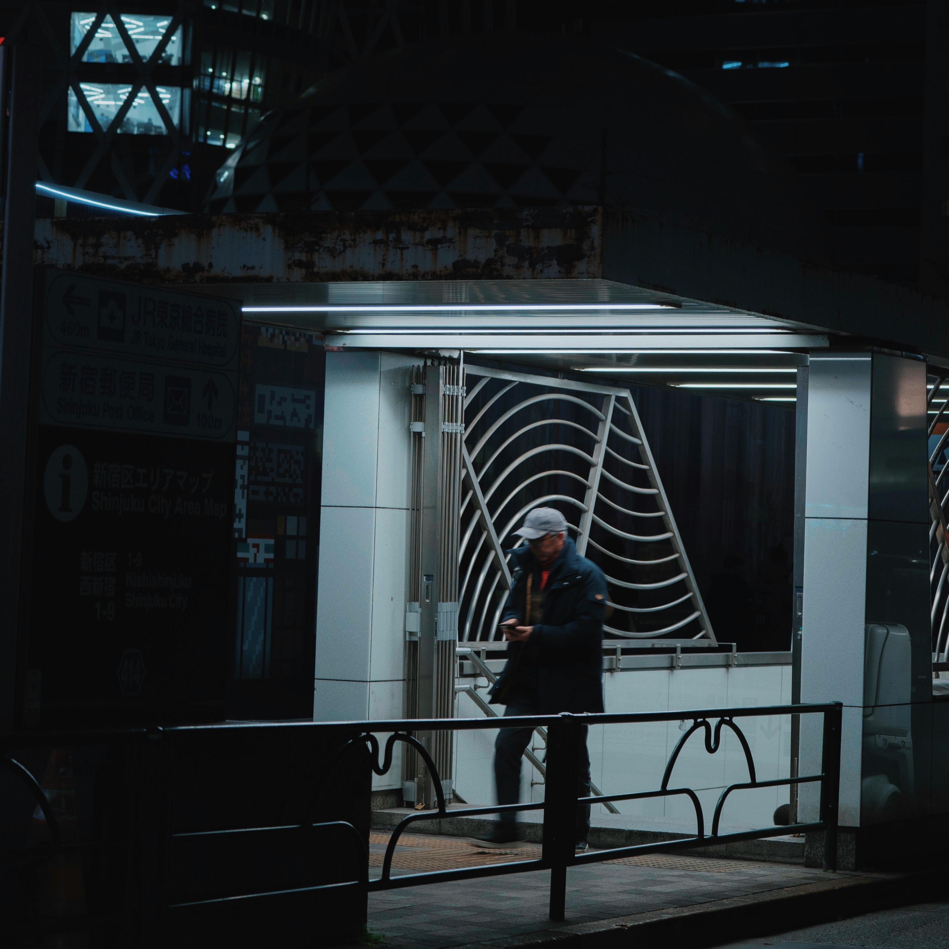 夜の駅前でベンチに立つ人