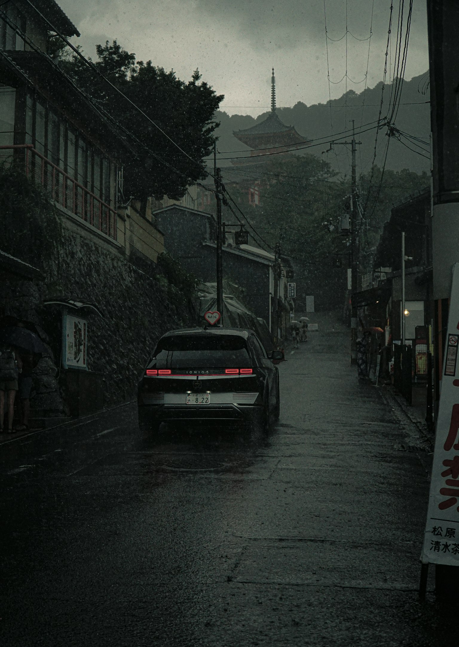 Une voiture sur une rue sombre avec des vieux bâtiments sous la pluie