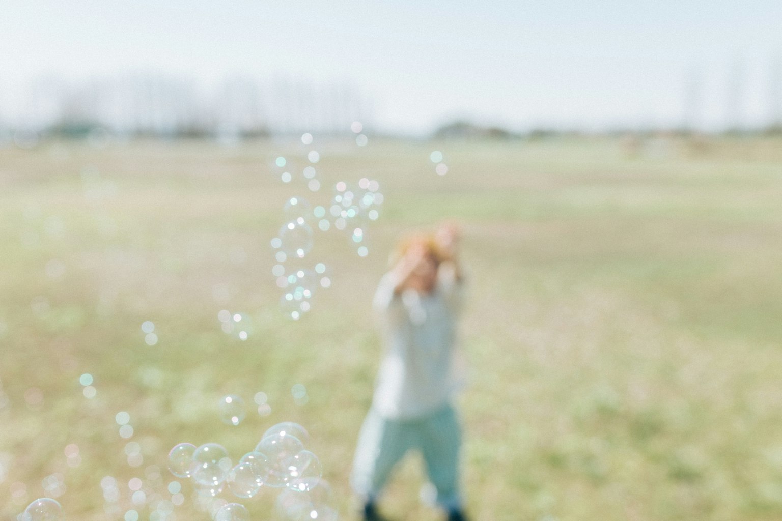 Child playing with bubbles in an open field