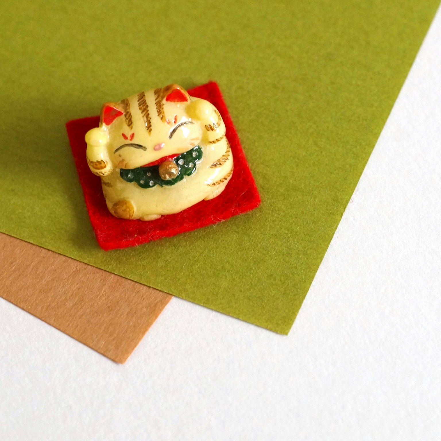 A small ceramic cat figurine with yellow stripes sitting on a red base