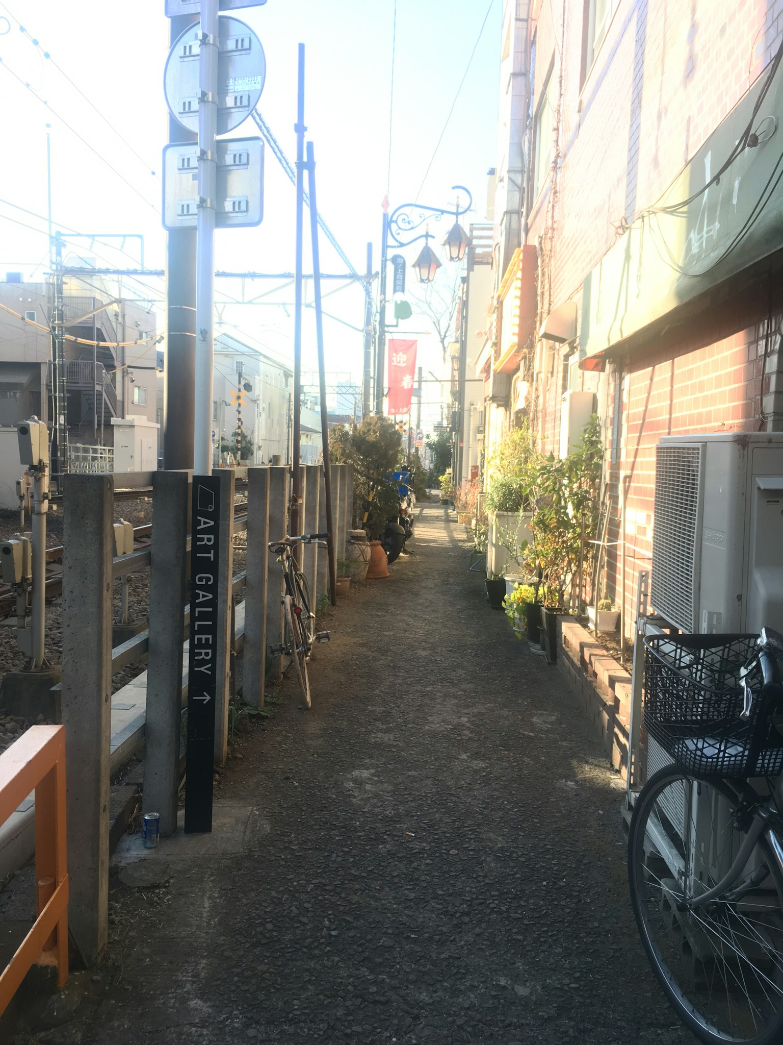 Lorong sempit dengan sepeda dan tanaman pot