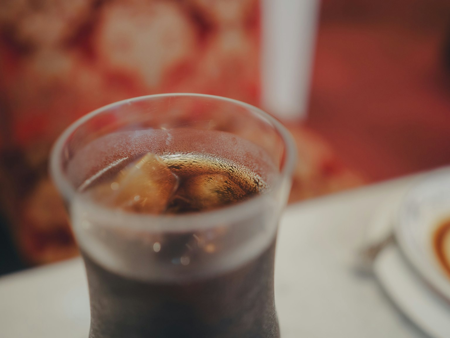 Verre de cola avec des glaçons et fond à motifs