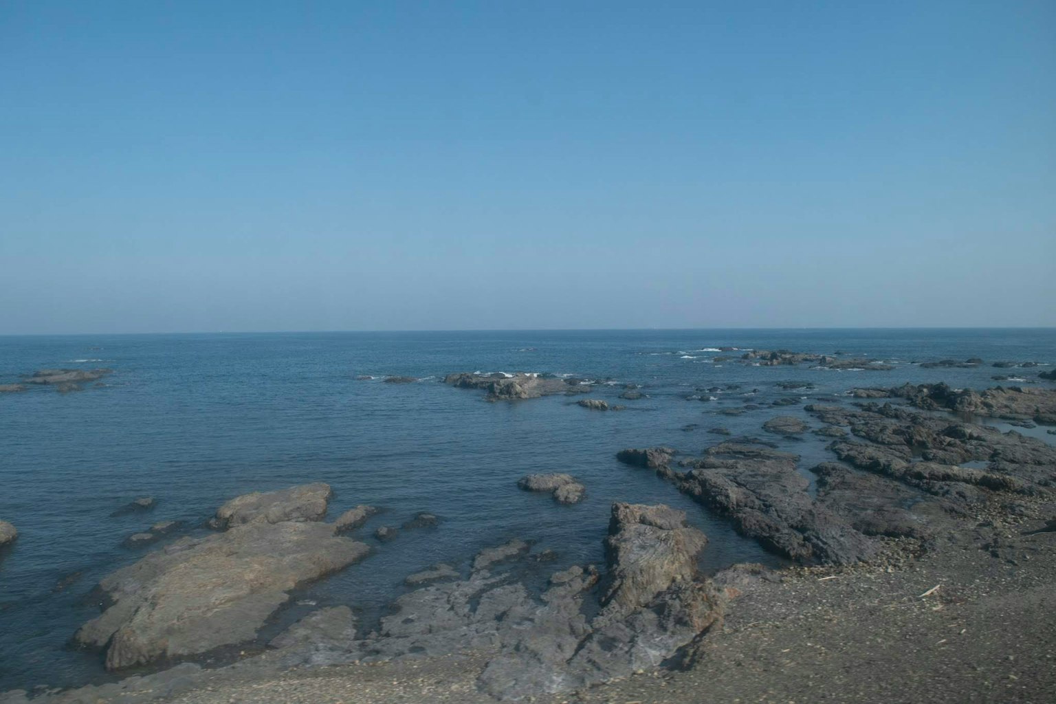 Malersicher Blick auf die felsige Küste und das ruhige Meer unter blauem Himmel