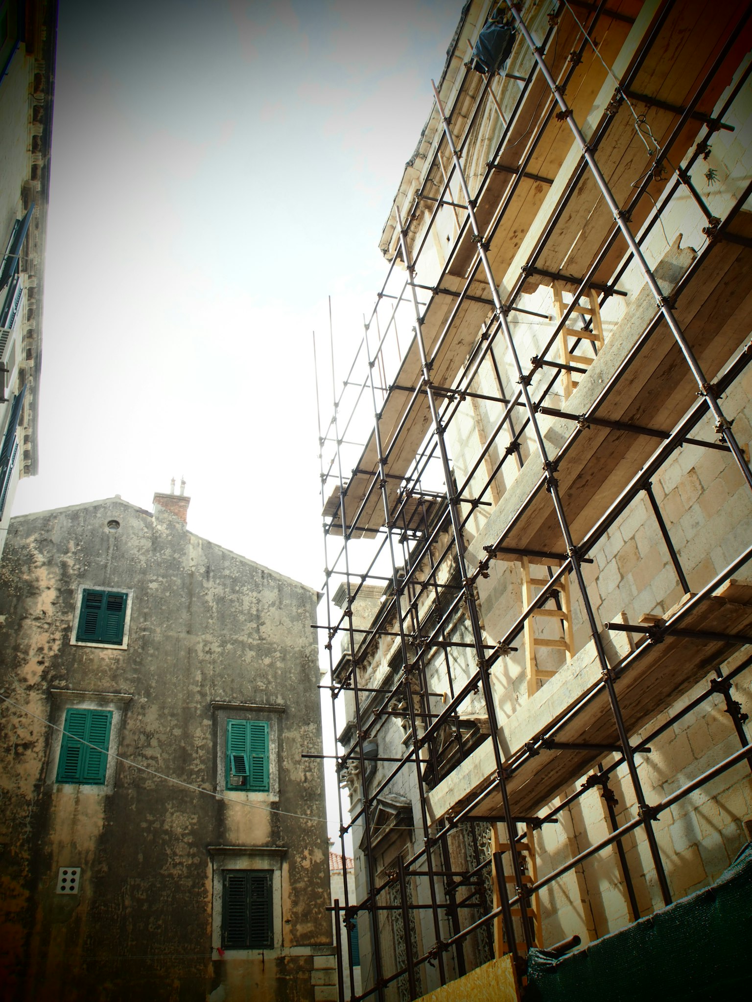 Contrasto tra un edificio ristrutturato e una vecchia struttura con ponteggio