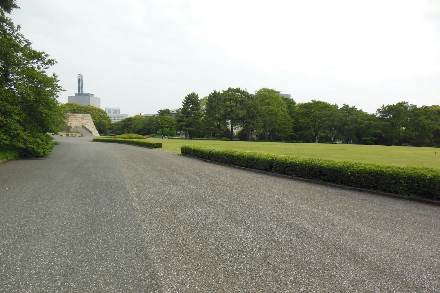 Weite Parkszene mit einem gepflasterten Weg und einer grünen Rasenfläche