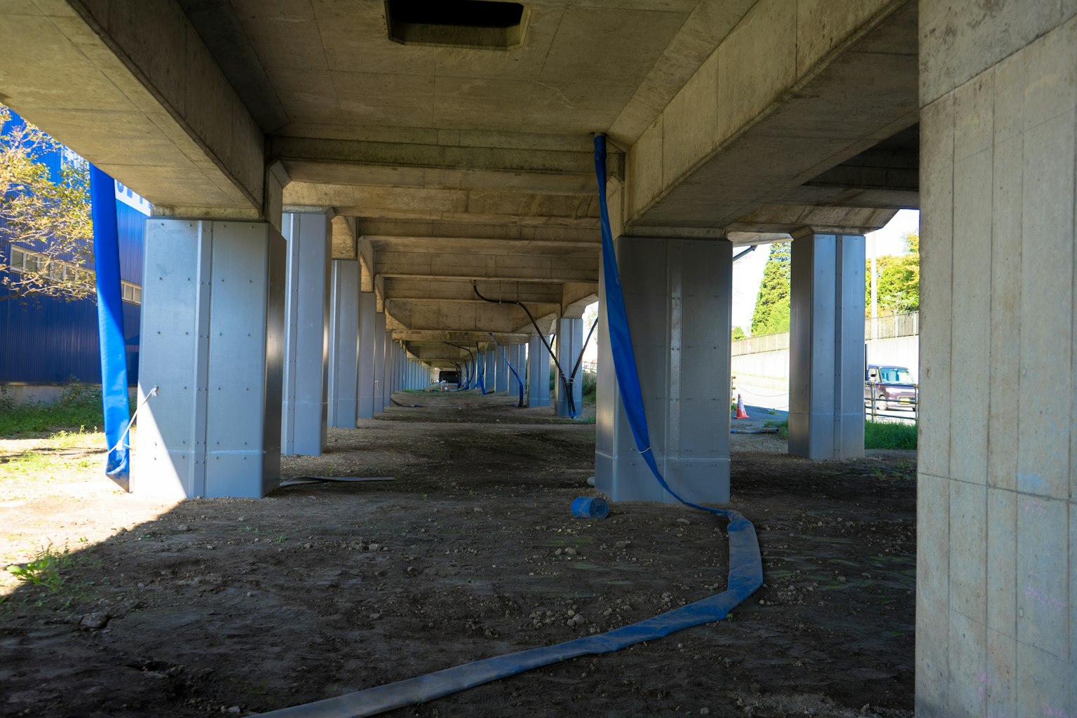Blick auf die Unterseite einer Betonbrücke mit herabhängendem blauen Stoff