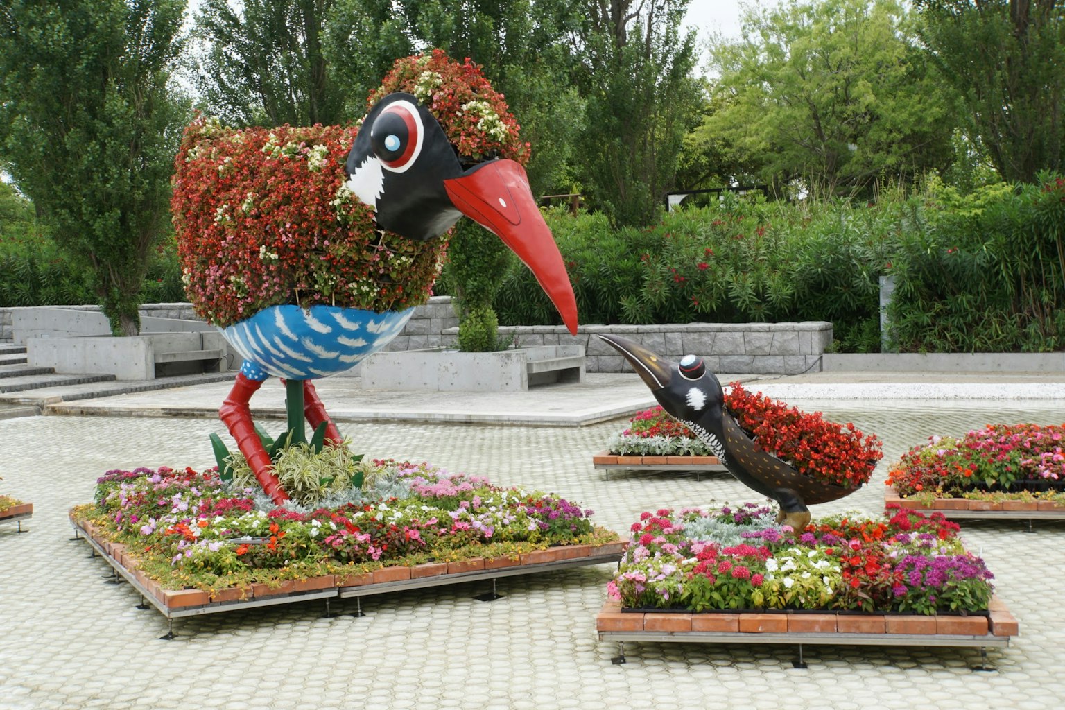 Garden scene featuring large and small bird sculptures decorated with flowers