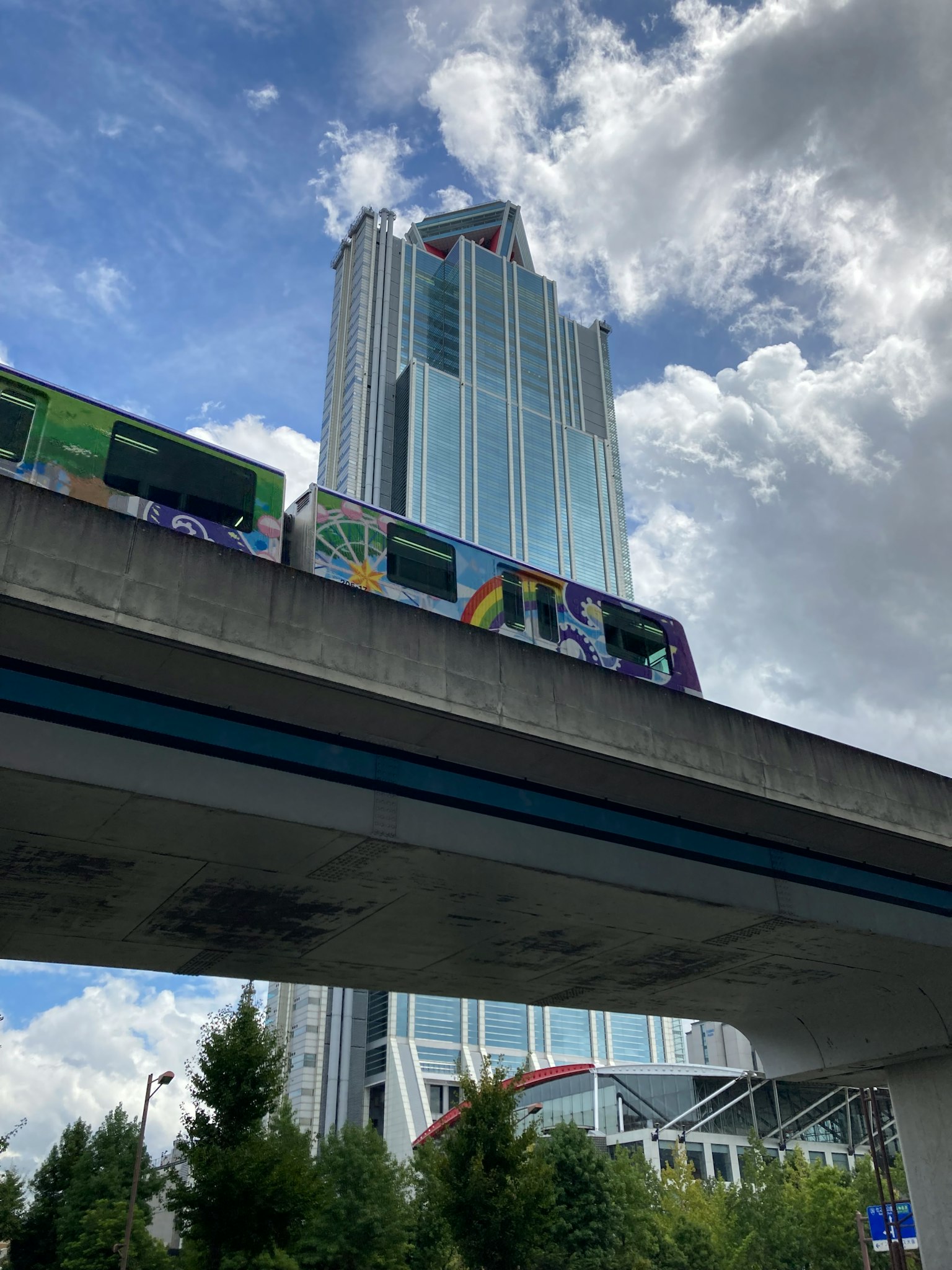 Un edificio alto con un monorriel que pasa por debajo bajo un cielo azul
