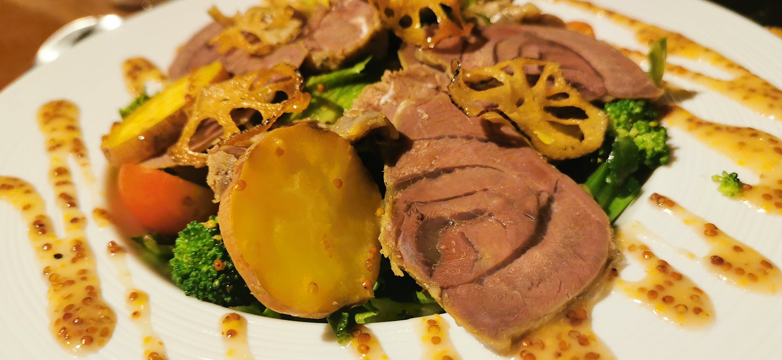 Hidangan dengan daging iris dan sayuran di atas salad