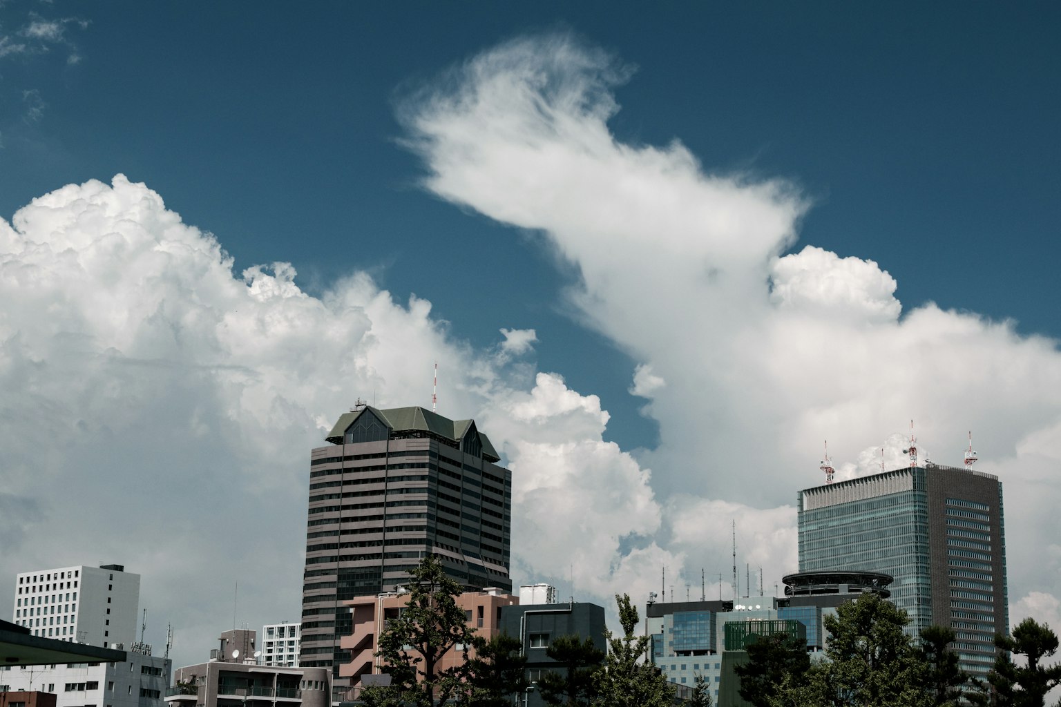 Skyline di città con grattacieli sotto un cielo blu e nuvole