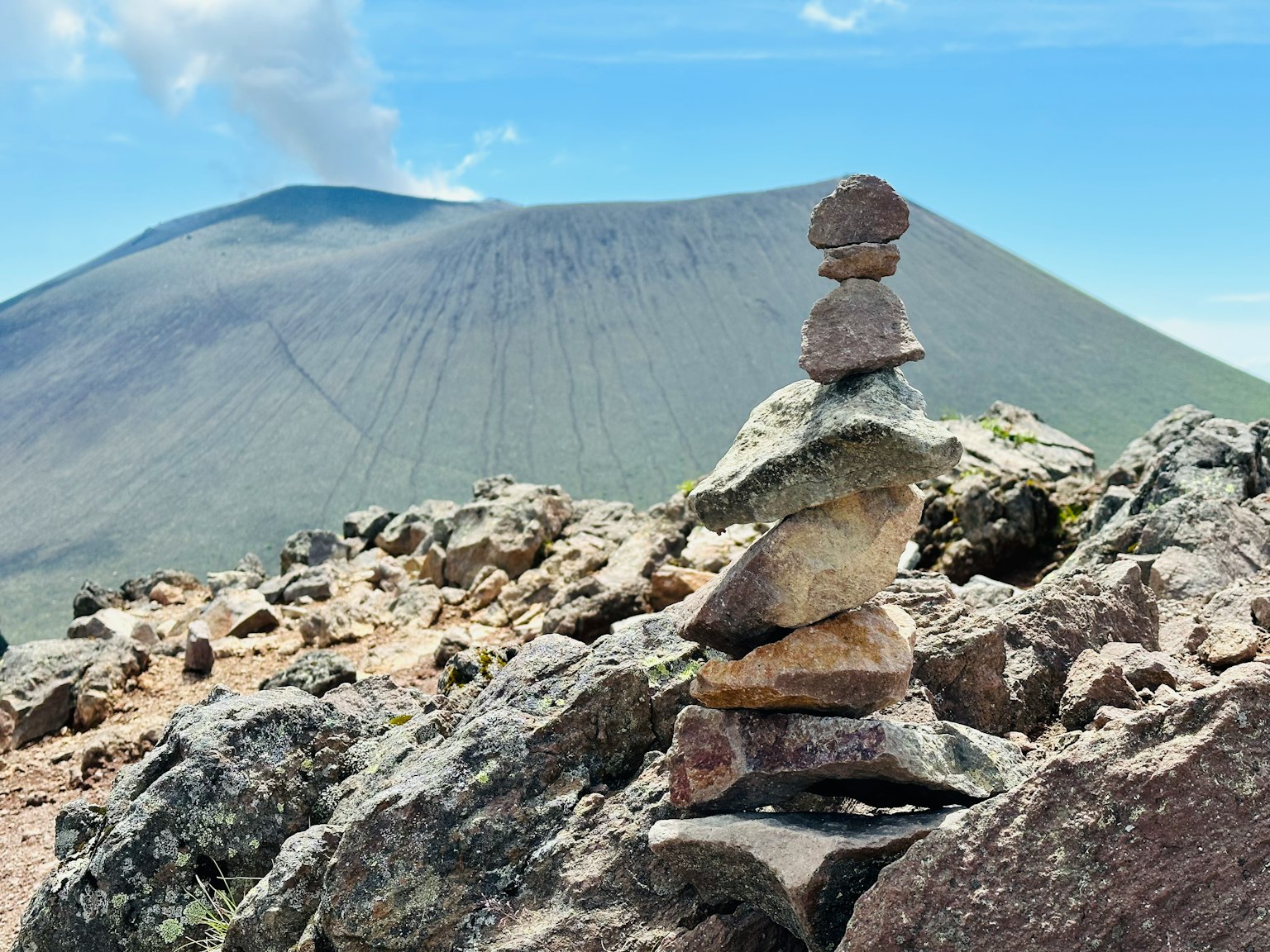 岩石上的石塔与背景中的火山