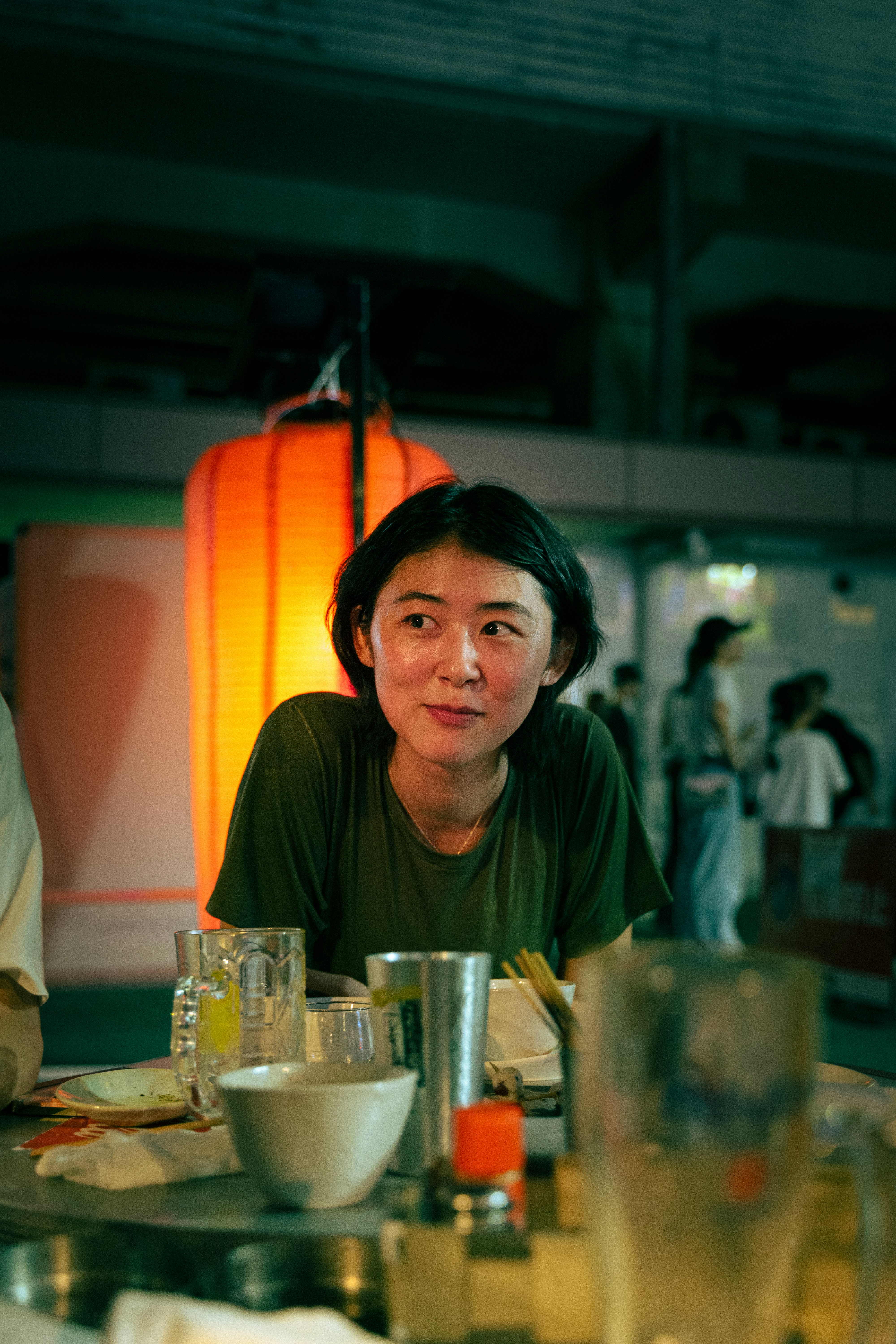 屋台のような店内で食卓を前にした女性の表情